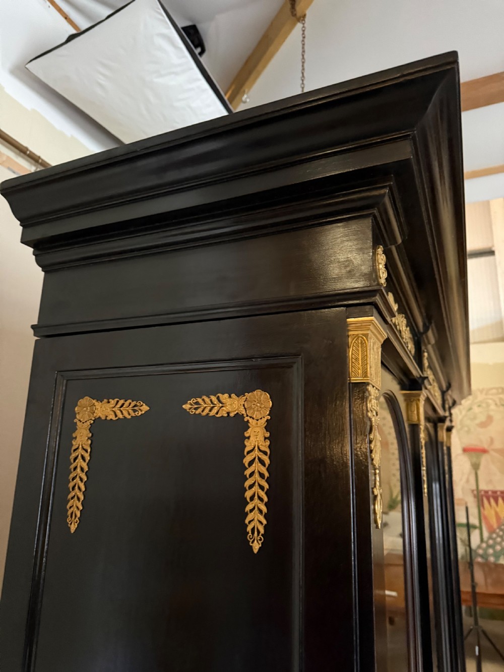 A large ebonised three-door glazed bookcase featuring gold-toned gilt-bronze mounts, arched glass panels, and an oak interior. View VI