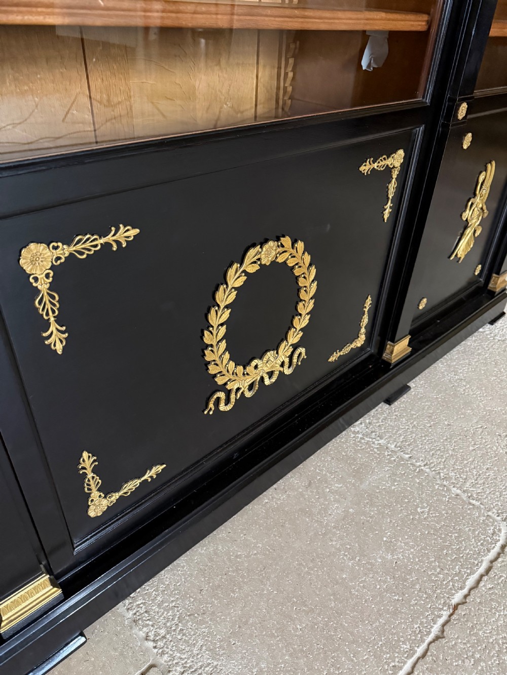 A large ebonised three-door glazed bookcase featuring gold-toned gilt-bronze mounts, arched glass panels, and an oak interior. View VIII