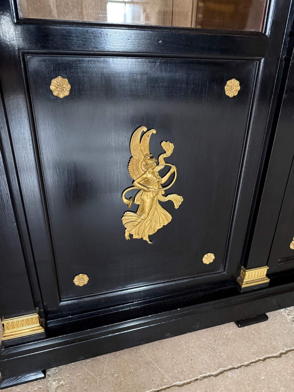 A large ebonised three-door glazed bookcase featuring gold-toned gilt-bronze mounts, arched glass panels, and an oak interior. View IX