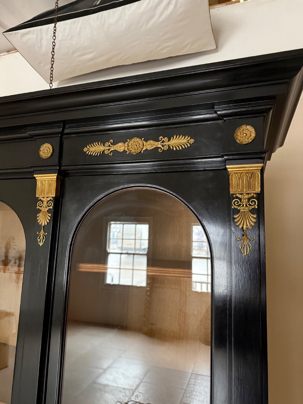 A large ebonised three-door glazed bookcase featuring gold-toned gilt-bronze mounts, arched glass panels, and an oak interior. View XVII
