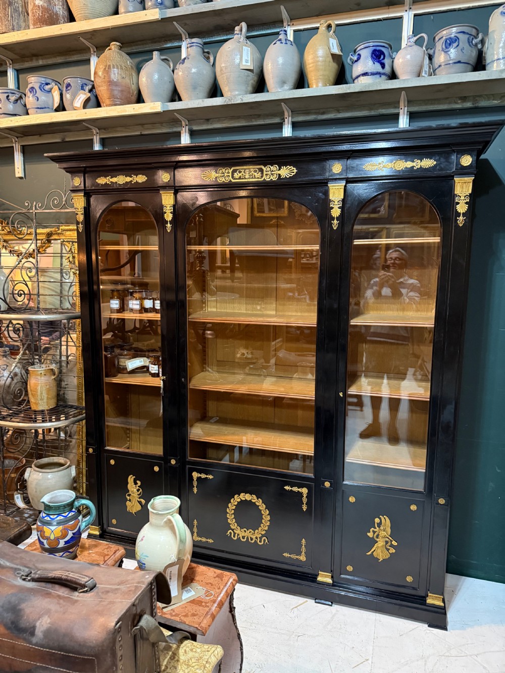 A large ebonised three-door glazed bookcase featuring gold-toned gilt-bronze mounts, arched glass panels, and an oak interior. View XVIII