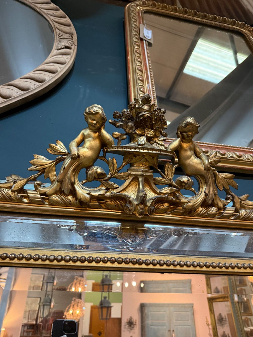 A 19th-century rectangular French giltwood wall mirror featuring elaborate cresting with cherubs, an urn finial, acanthus leaf scrolling, and a beaded inner border around a bevelled glass plate. View II