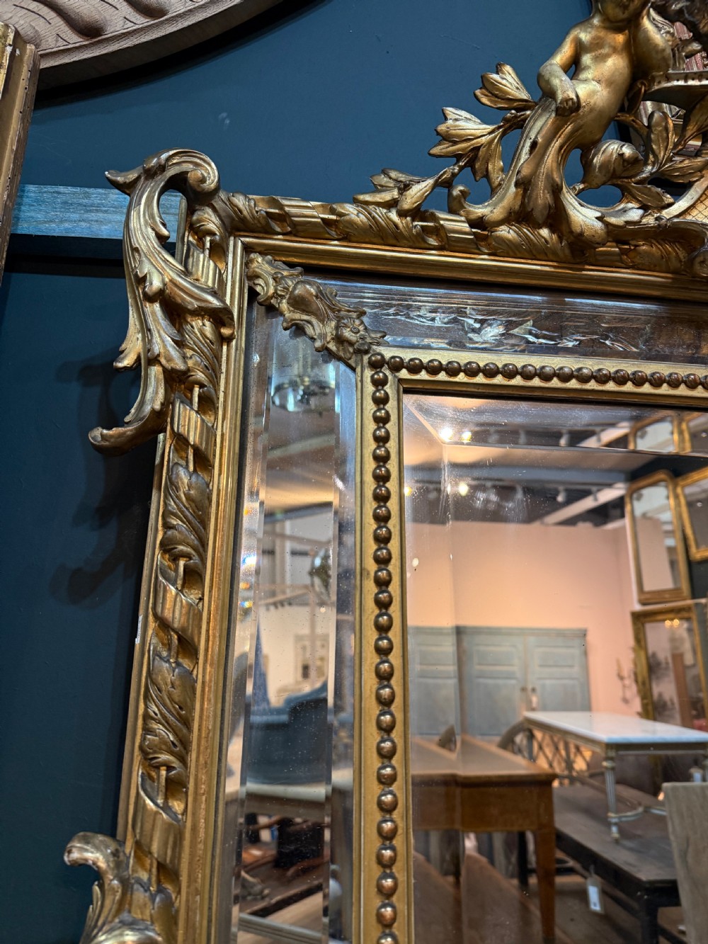 A 19th-century rectangular French giltwood wall mirror featuring elaborate cresting with cherubs, an urn finial, acanthus leaf scrolling, and a beaded inner border around a bevelled glass plate. View III