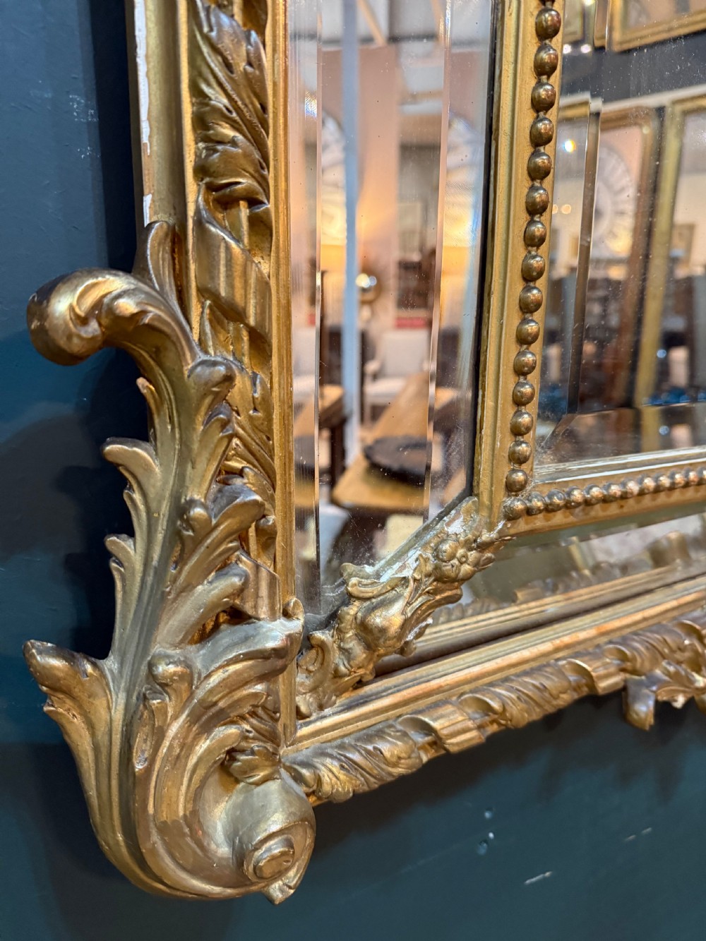 A 19th-century rectangular French giltwood wall mirror featuring elaborate cresting with cherubs, an urn finial, acanthus leaf scrolling, and a beaded inner border around a bevelled glass plate. View V