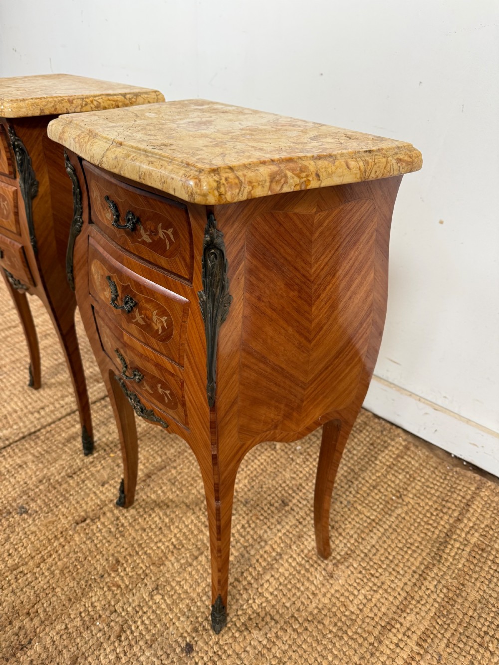 A pair of French Louis XV style bedside cabinets featuring variegated yellow marble tops, three marquetry inlaid drawers, brass mounts, and slender cabriole legs. View III