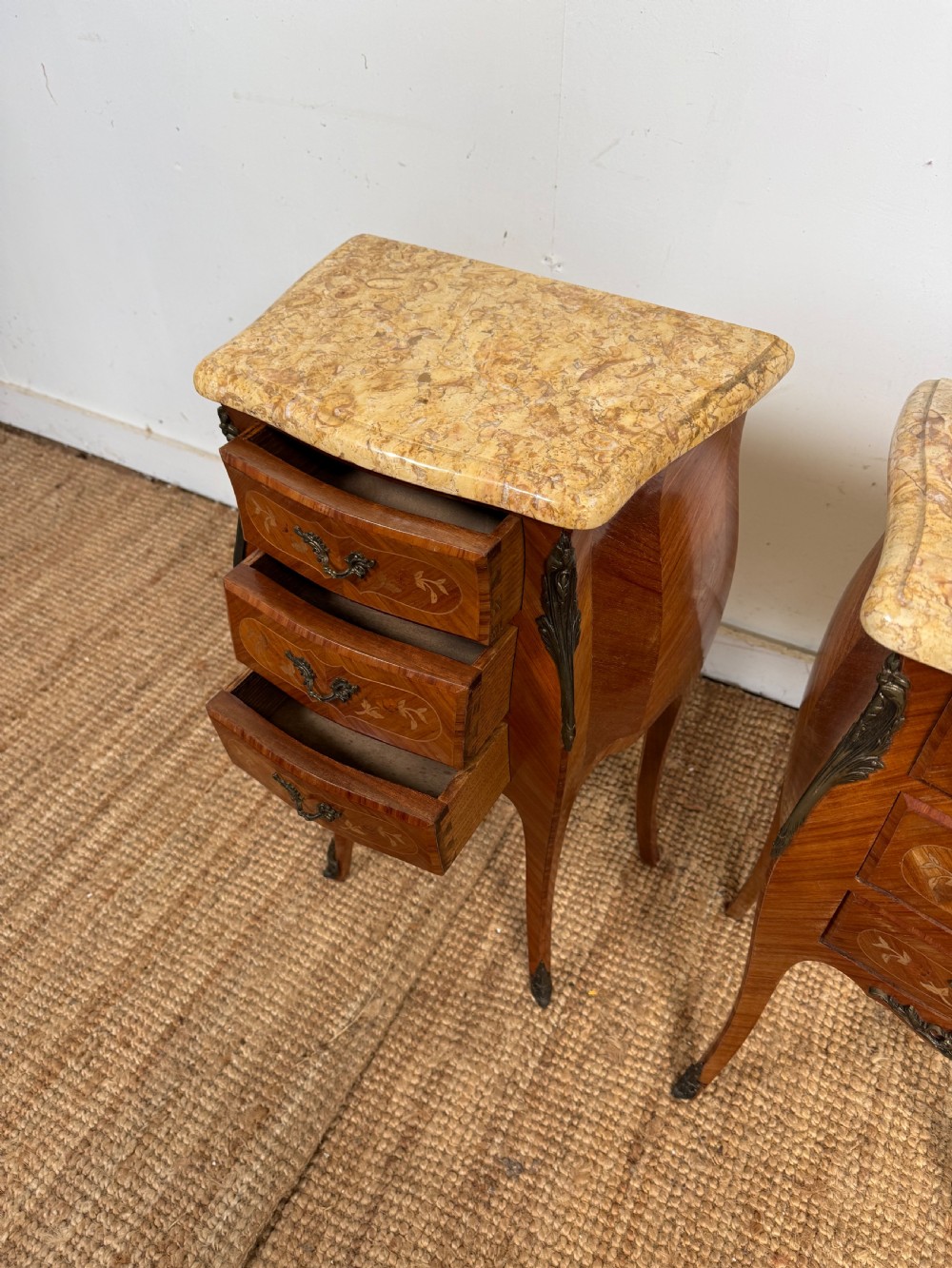 A pair of French Louis XV style bedside cabinets featuring variegated yellow marble tops, three marquetry inlaid drawers, brass mounts, and slender cabriole legs. View V