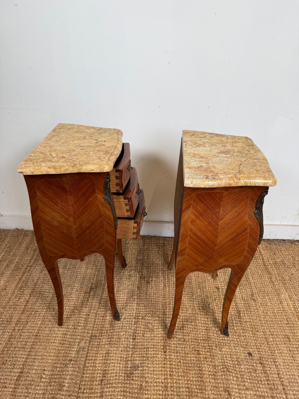 A pair of French Louis XV style bedside cabinets featuring variegated yellow marble tops, three marquetry inlaid drawers, brass mounts, and slender cabriole legs. View IX