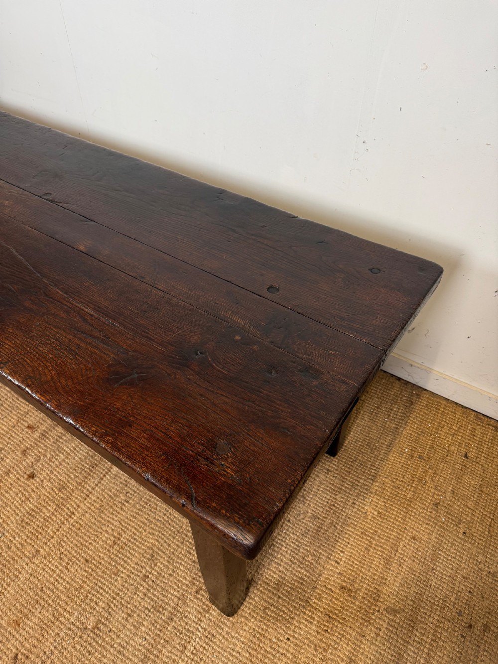 A long 18th century dark oak farmhouse dining table with a thick plank top and square legs. View II