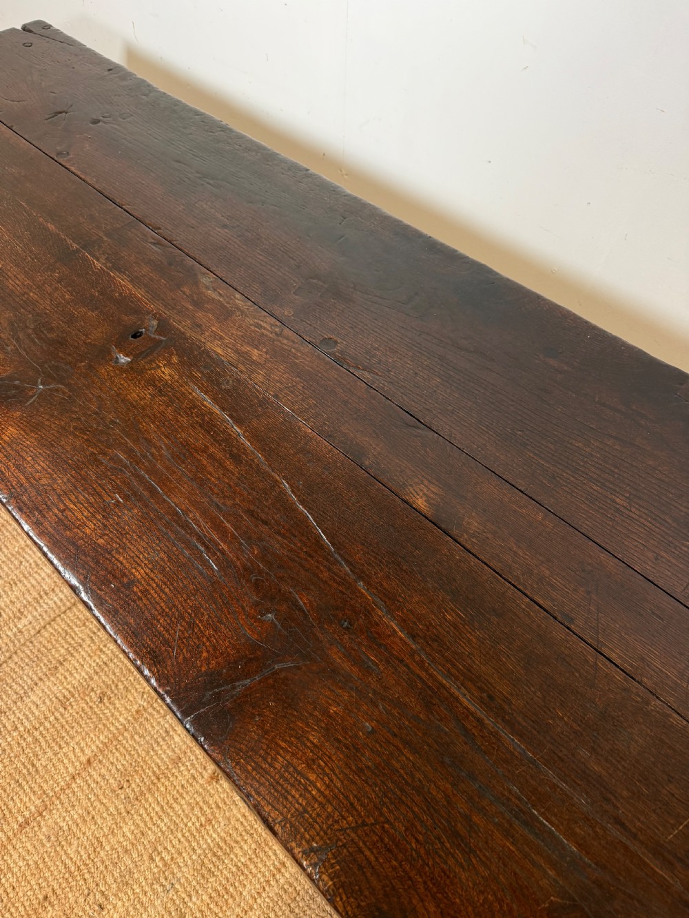 A long 18th century dark oak farmhouse dining table with a thick plank top and square legs. View IV