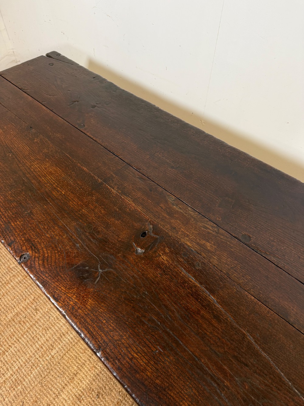 A long 18th century dark oak farmhouse dining table with a thick plank top and square legs. View V