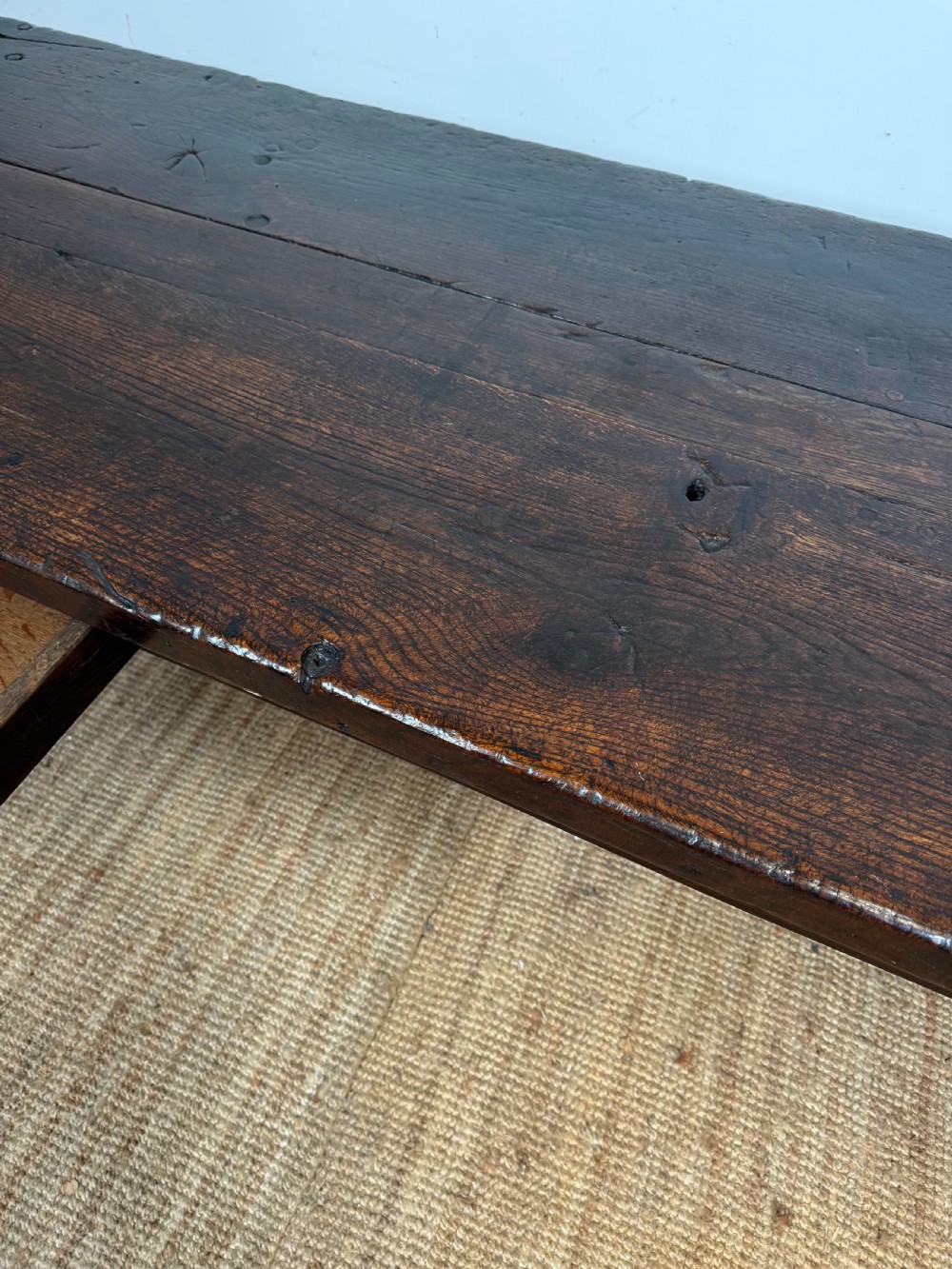 A long 18th century dark oak farmhouse dining table with a thick plank top and square legs. View X