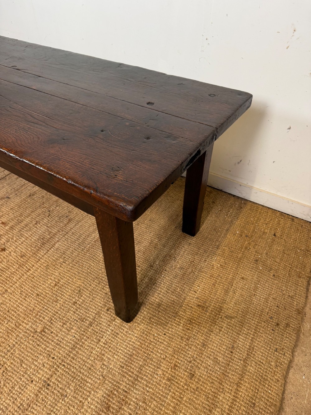 A long 18th century dark oak farmhouse dining table with a thick plank top and square legs. View XII