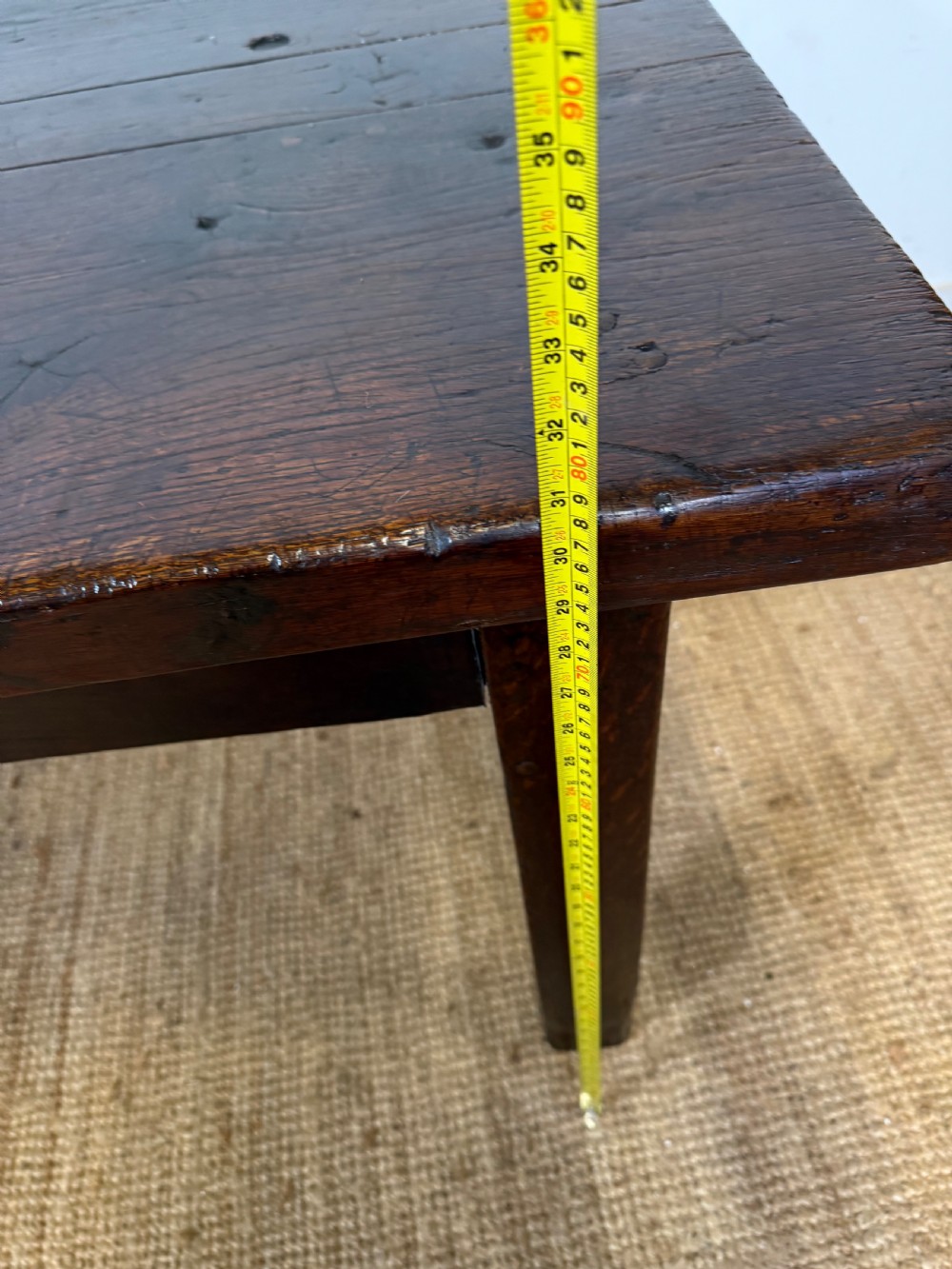A long 18th century dark oak farmhouse dining table with a thick plank top and square legs. View XV