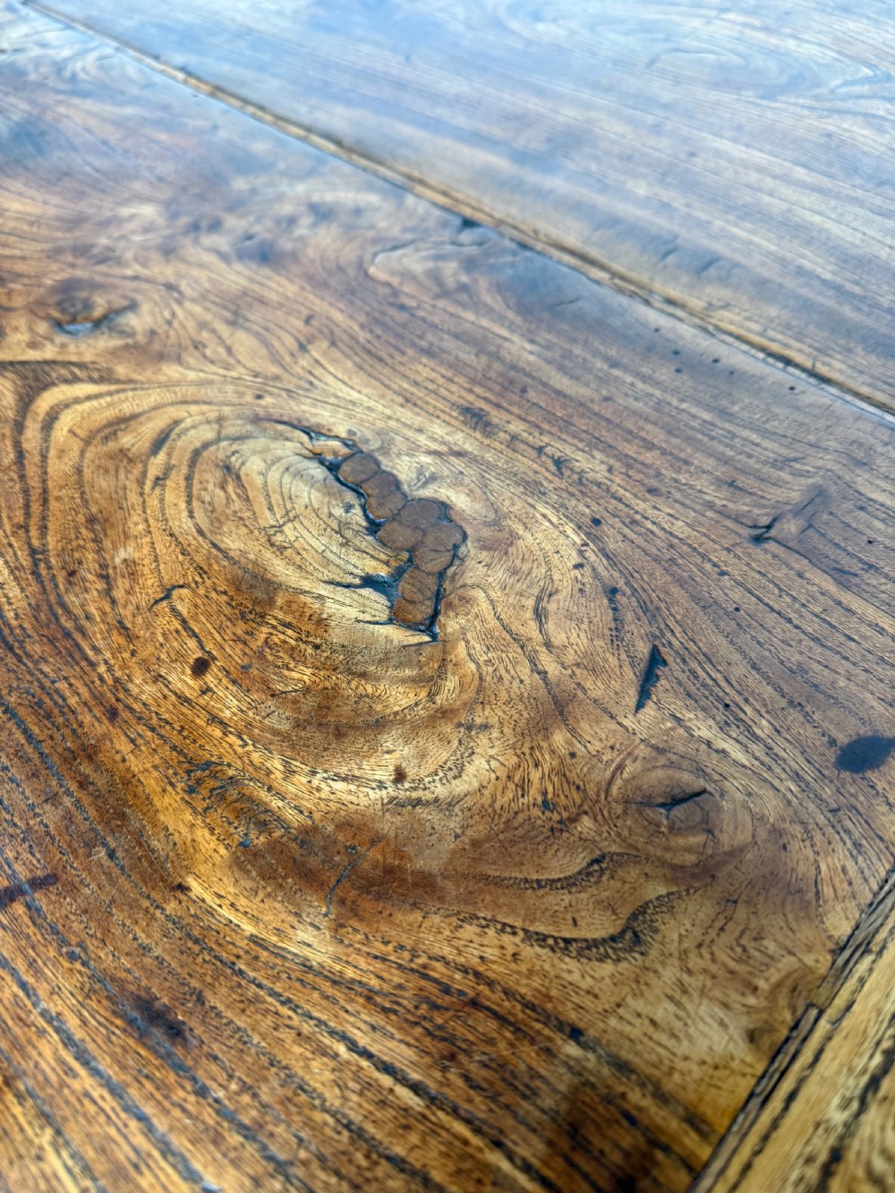 A long 19th-century rustic elm farmhouse dining table featuring a solid plank top and lower support stretchers. View V