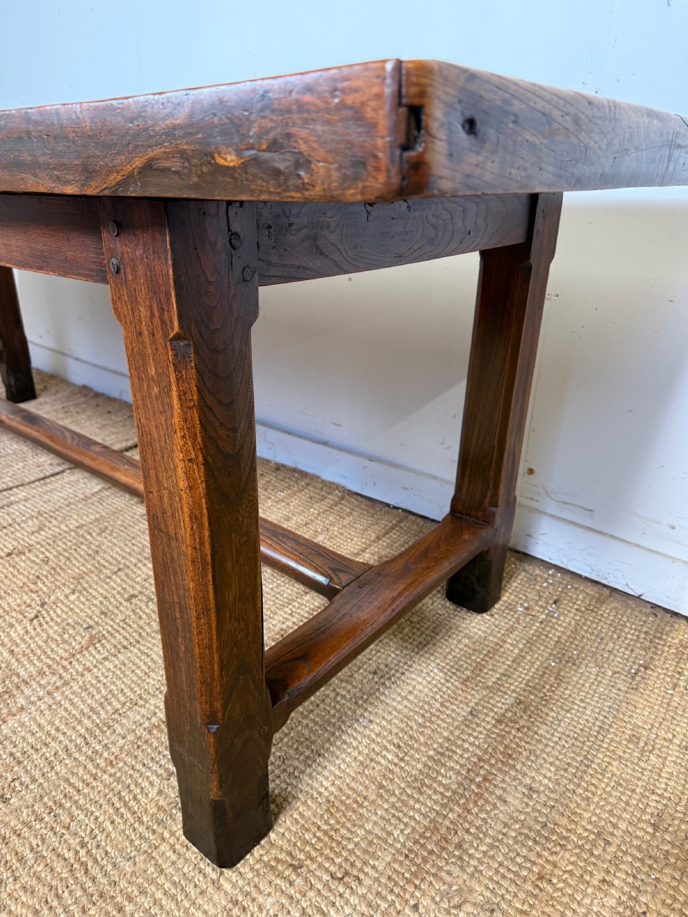 A long 19th-century rustic elm farmhouse dining table featuring a solid plank top and lower support stretchers. View VI