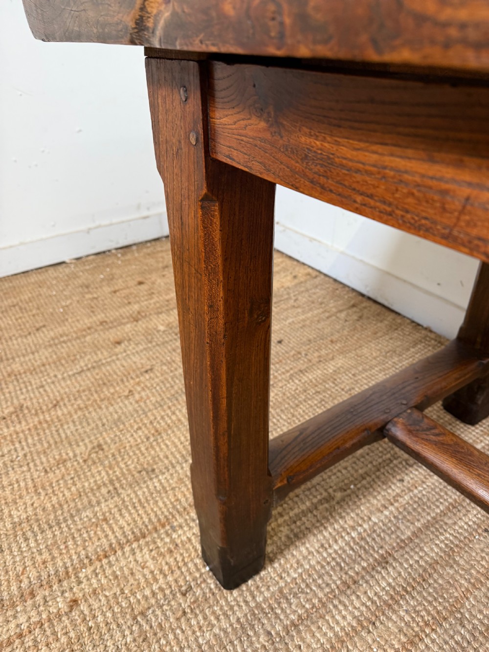 A long 19th-century rustic elm farmhouse dining table featuring a solid plank top and lower support stretchers. View VII