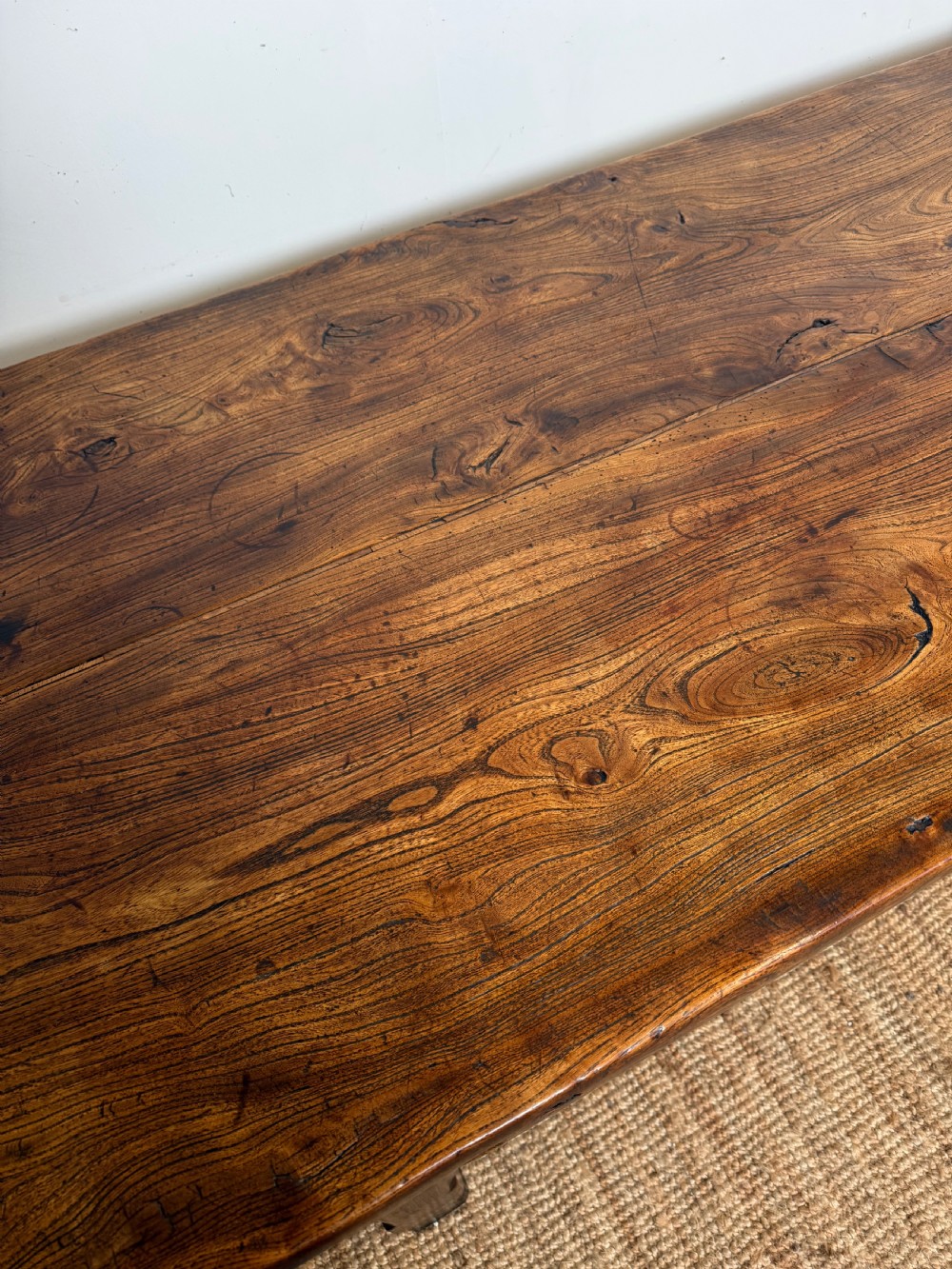 A long 19th-century rustic elm farmhouse dining table featuring a solid plank top and lower support stretchers. View X