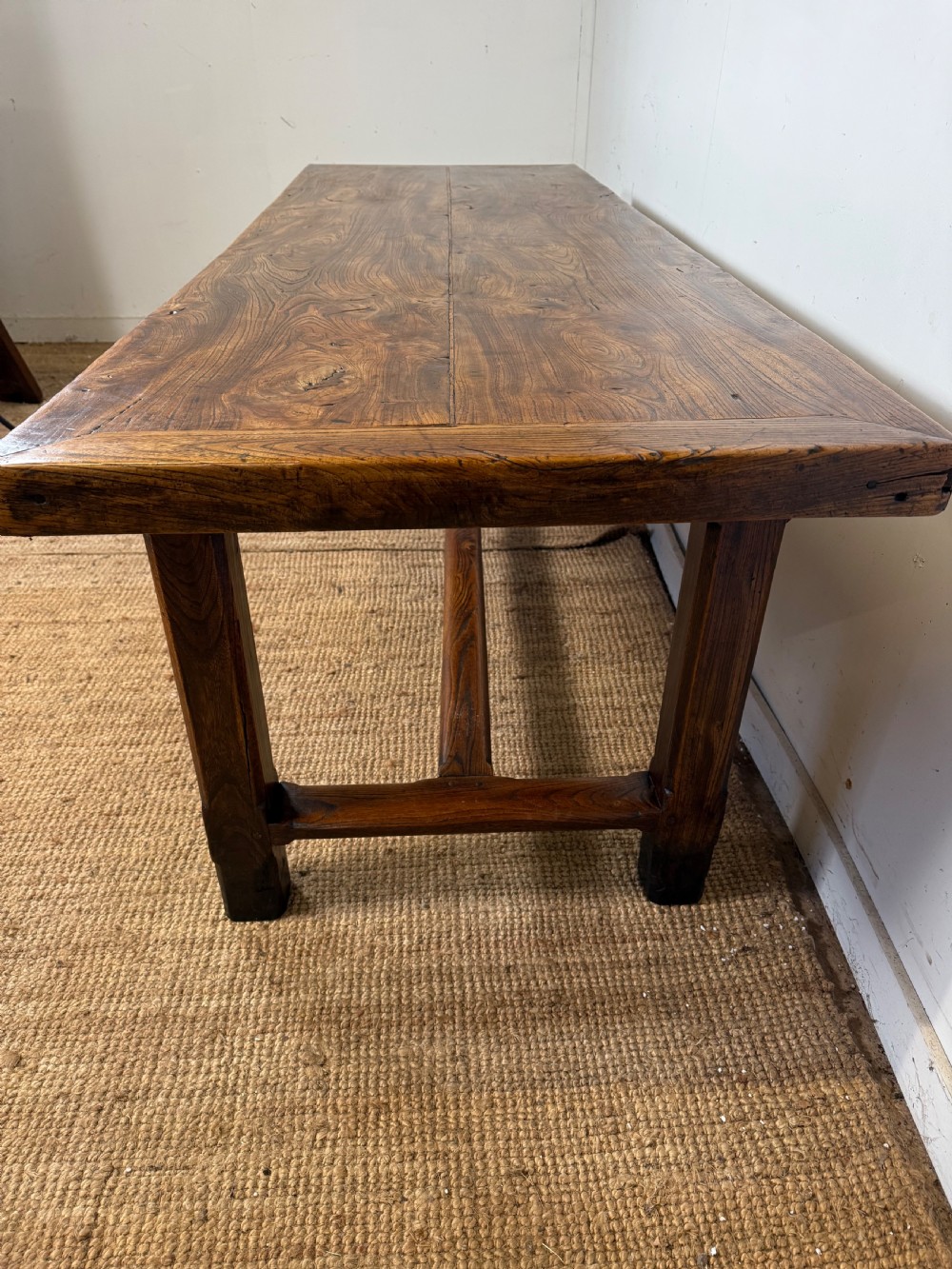 A long 19th-century rustic elm farmhouse dining table featuring a solid plank top and lower support stretchers. View XIV