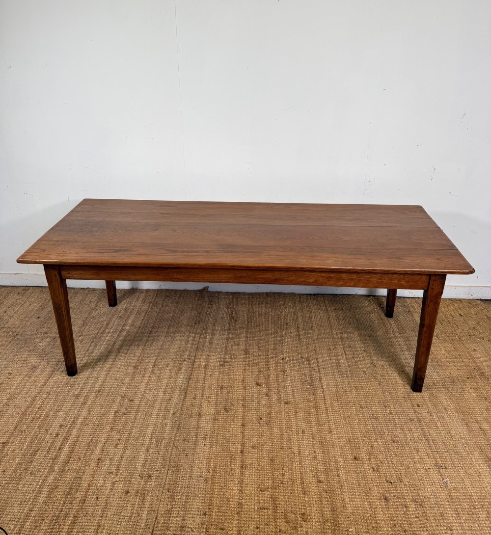 A rectangular late 19th-century chestnut farmhouse table featuring a plank top and four straight tapered legs.