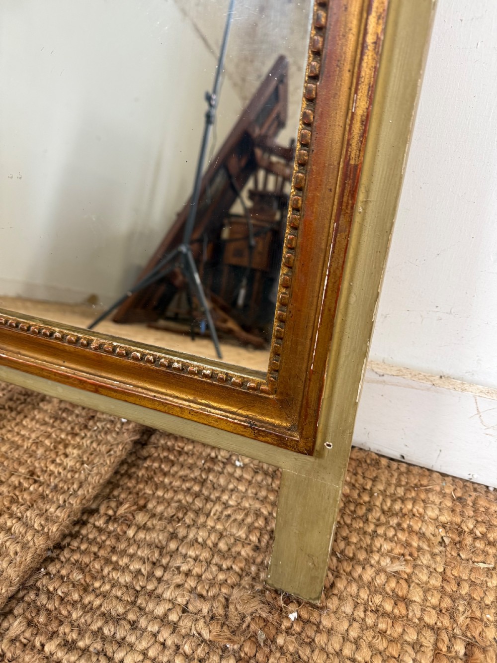 A compact Louis XVI style wall mirror featuring a gilded carved wood frame with beaded moulding and a prominent floral crest. View III