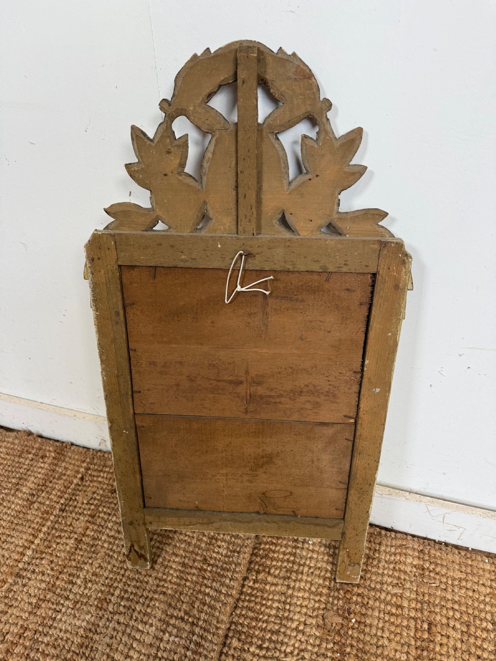 A compact Louis XVI style wall mirror featuring a gilded carved wood frame with beaded moulding and a prominent floral crest. View V