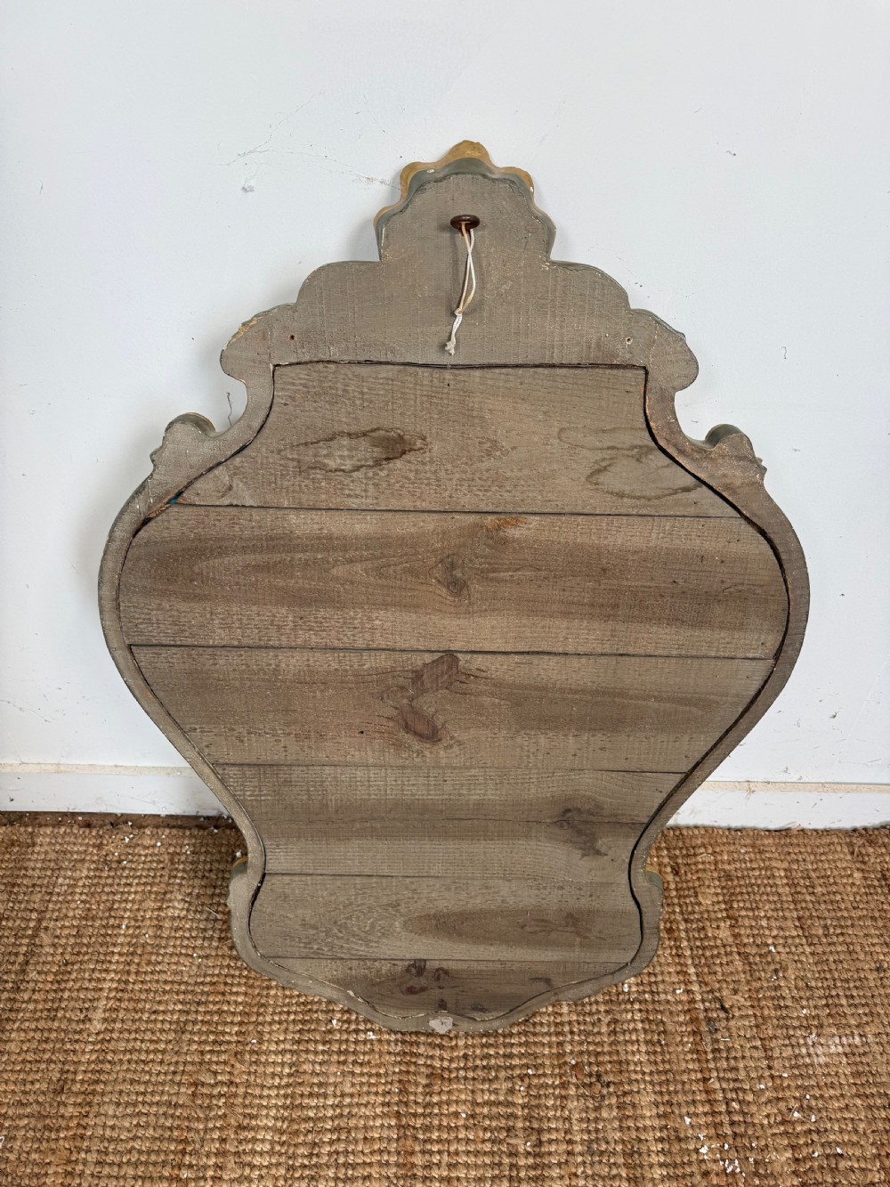 A French style carved giltwood wall mirror featuring an ornate shell crest and C-scroll border around an asymmetrical glass pane. View X