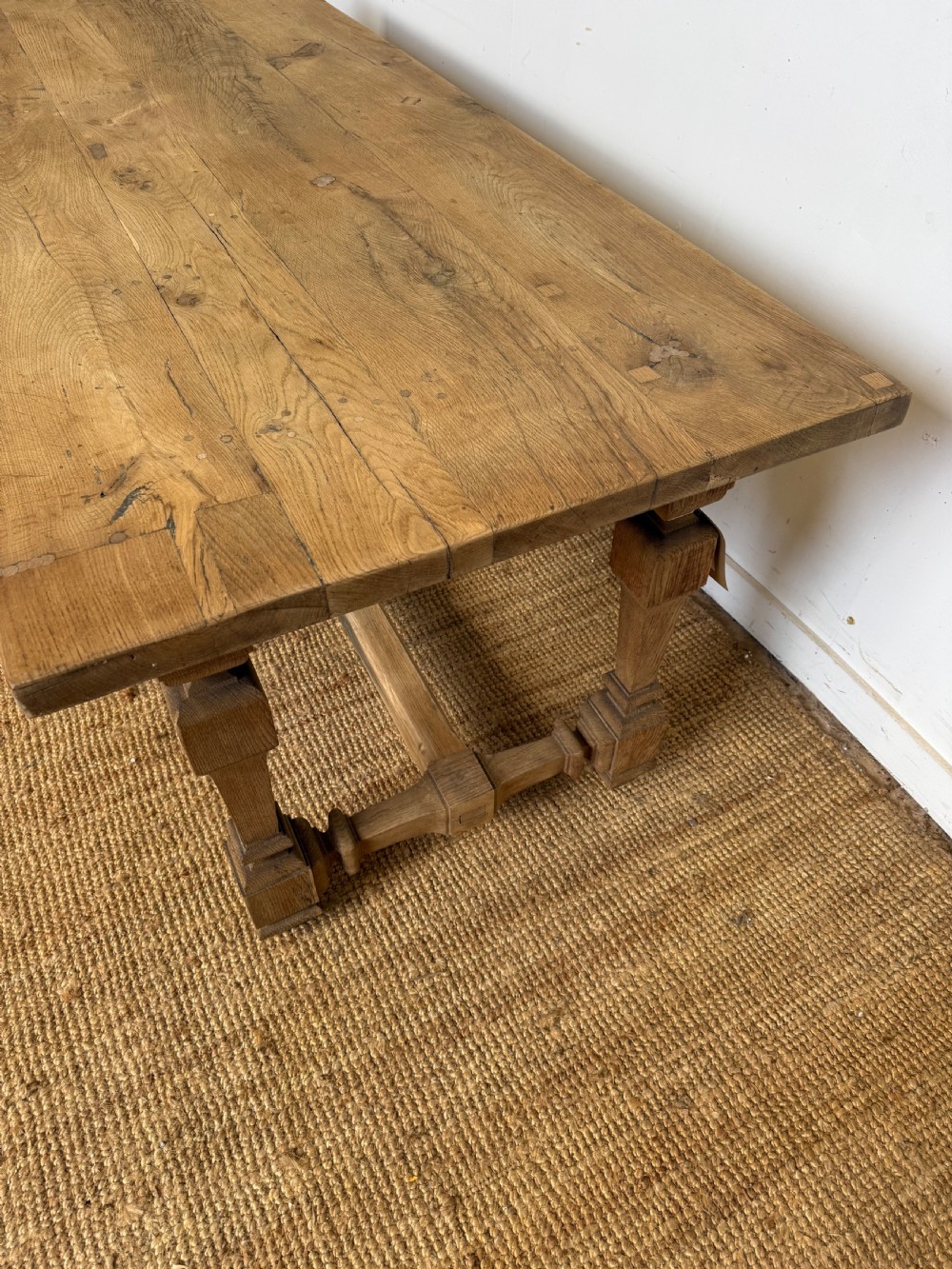 A long rectangular scrubbed oak refectory table featuring a solid top and trestle base with a low central stretcher. View III