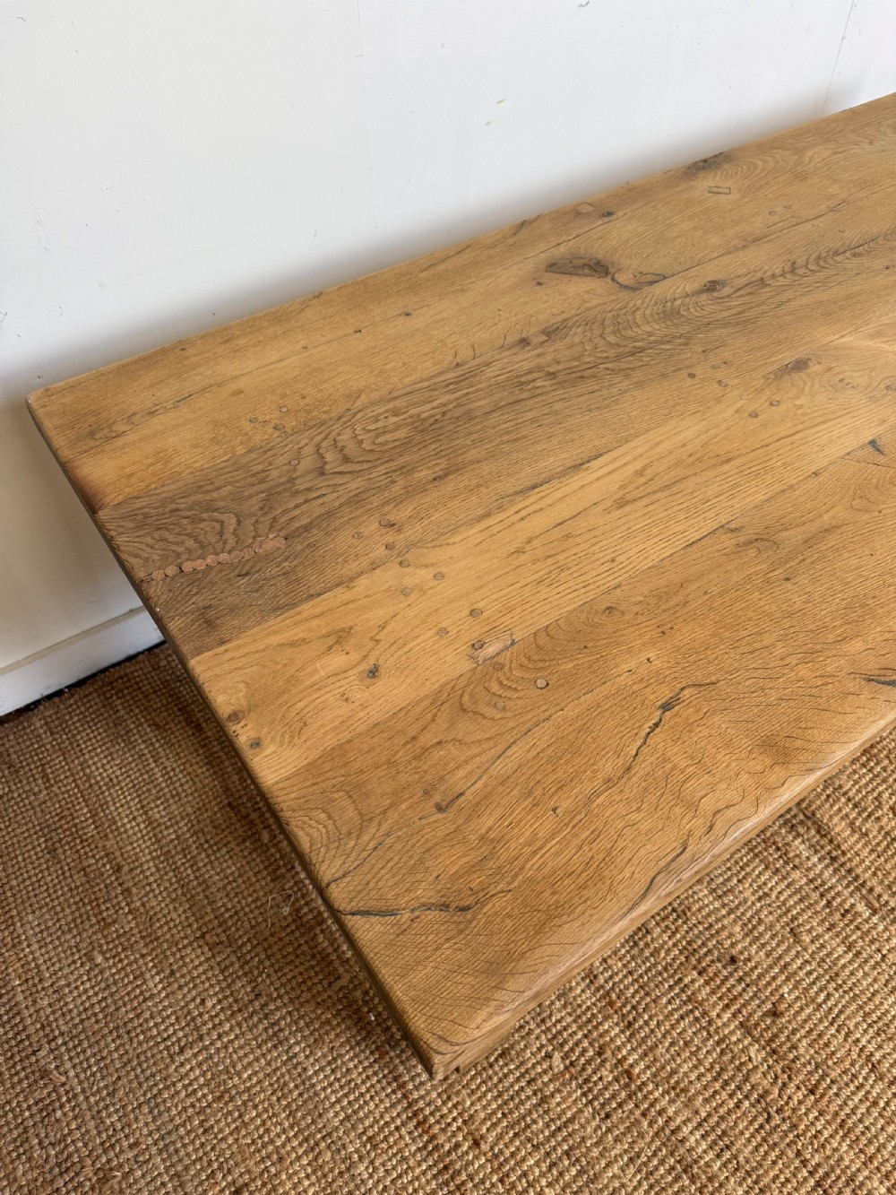 A long rectangular scrubbed oak refectory table featuring a solid top and trestle base with a low central stretcher. View V