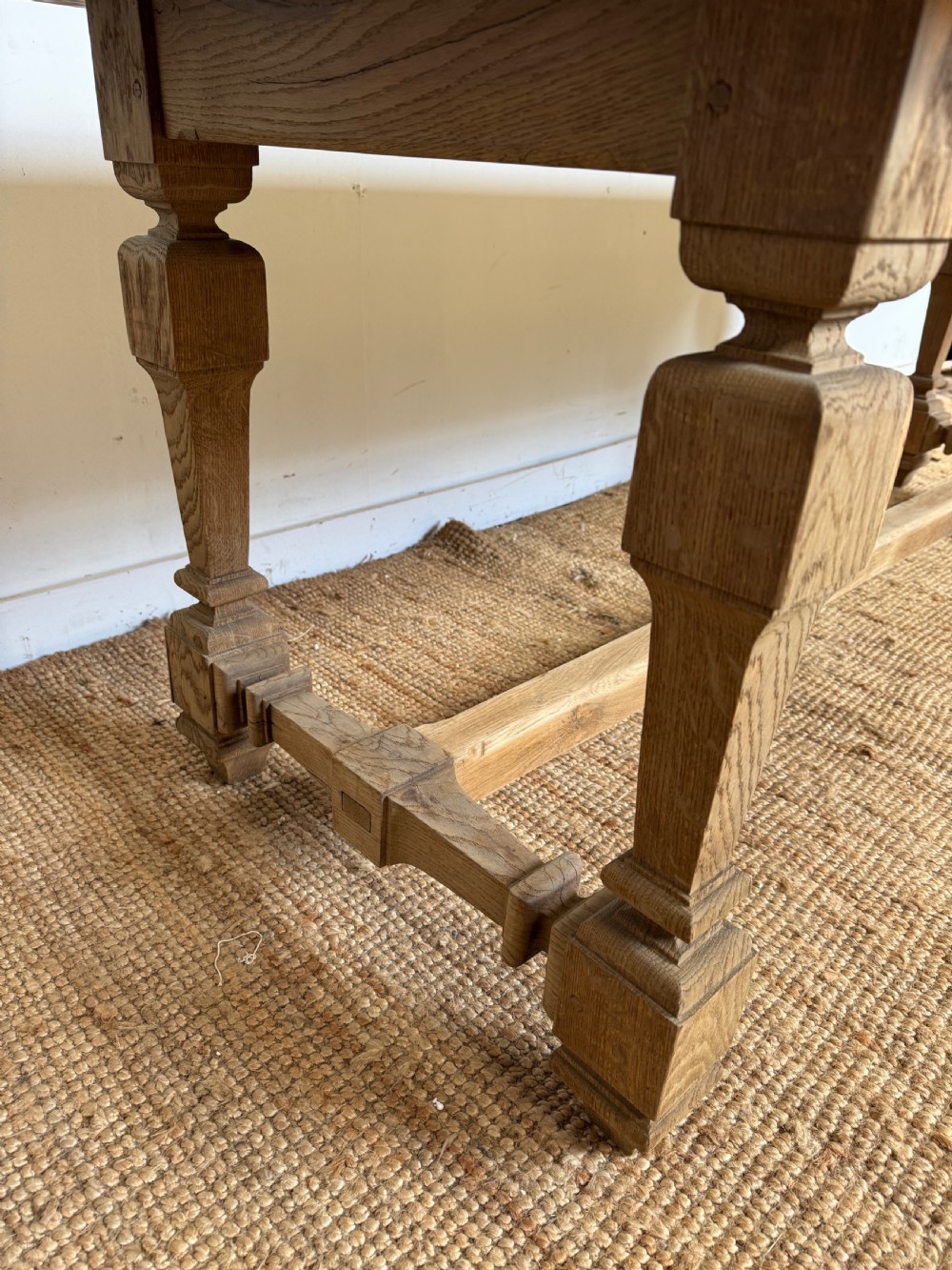 A long rectangular scrubbed oak refectory table featuring a solid top and trestle base with a low central stretcher. View X