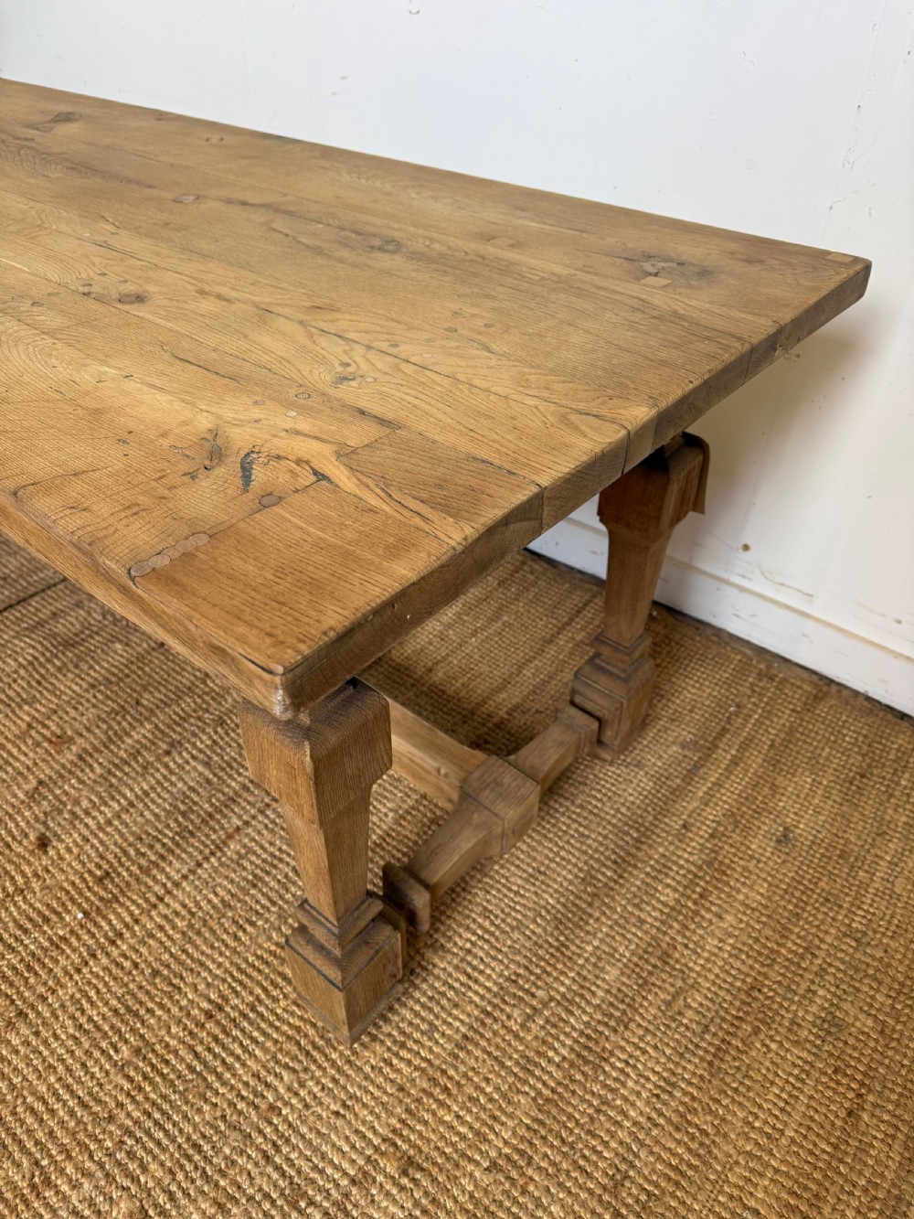 A long rectangular scrubbed oak refectory table featuring a solid top and trestle base with a low central stretcher. View XII