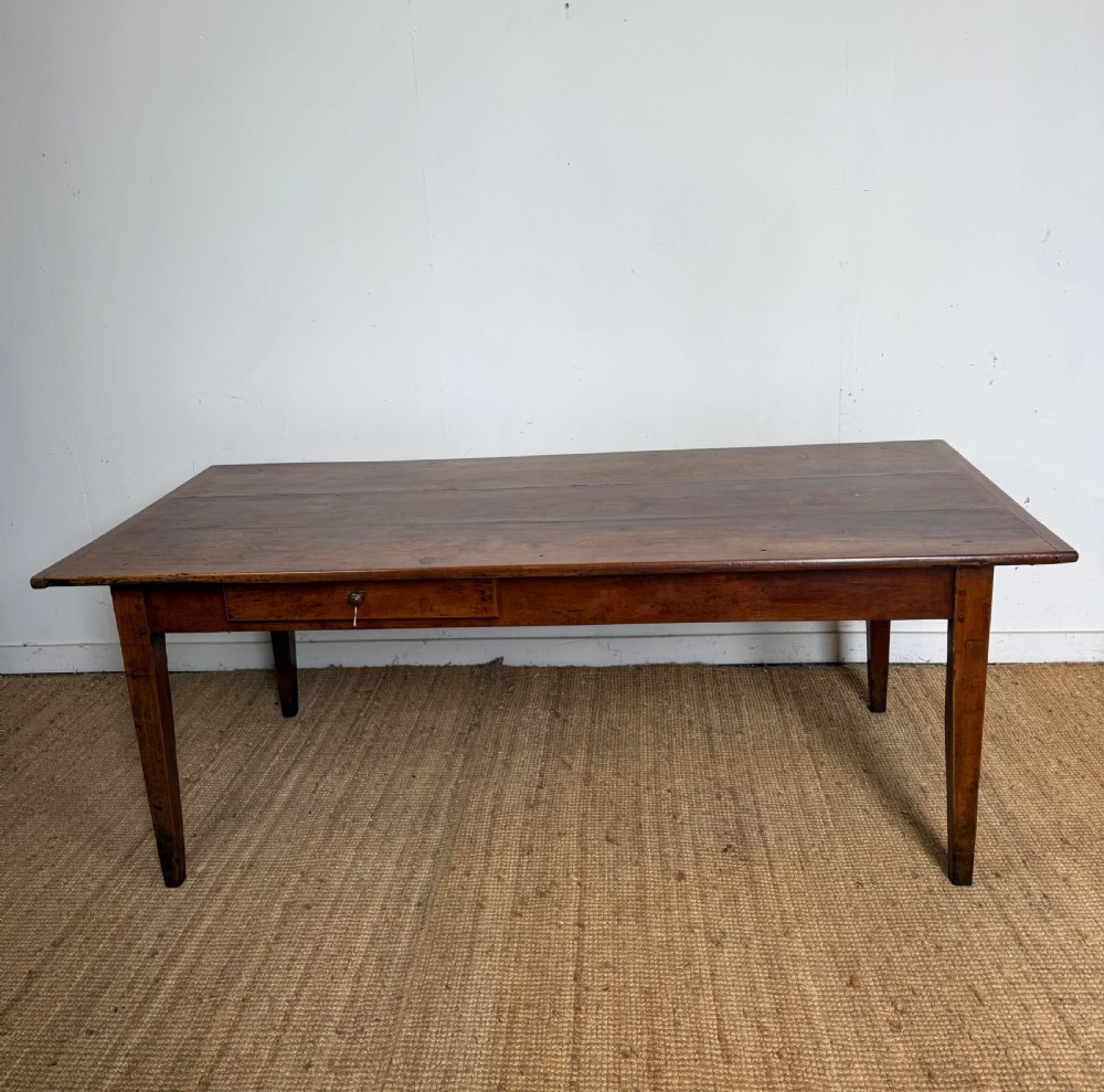 An antique French cherrywood farmhouse dining table featuring a plank top, single frieze drawer, and four square tapered legs. View II