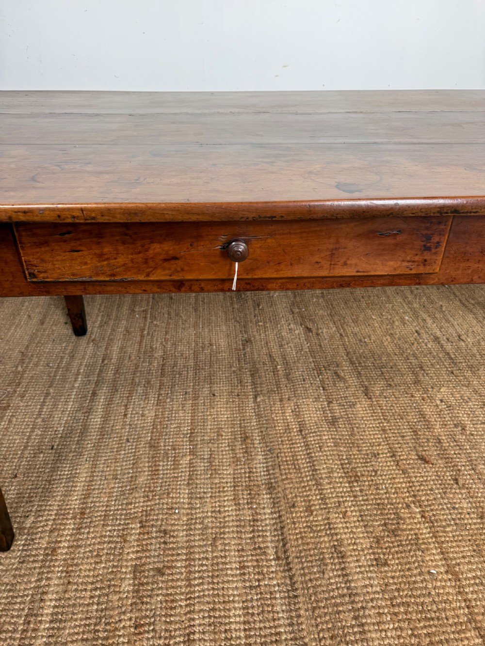 An antique French cherrywood farmhouse dining table featuring a plank top, single frieze drawer, and four square tapered legs. View III