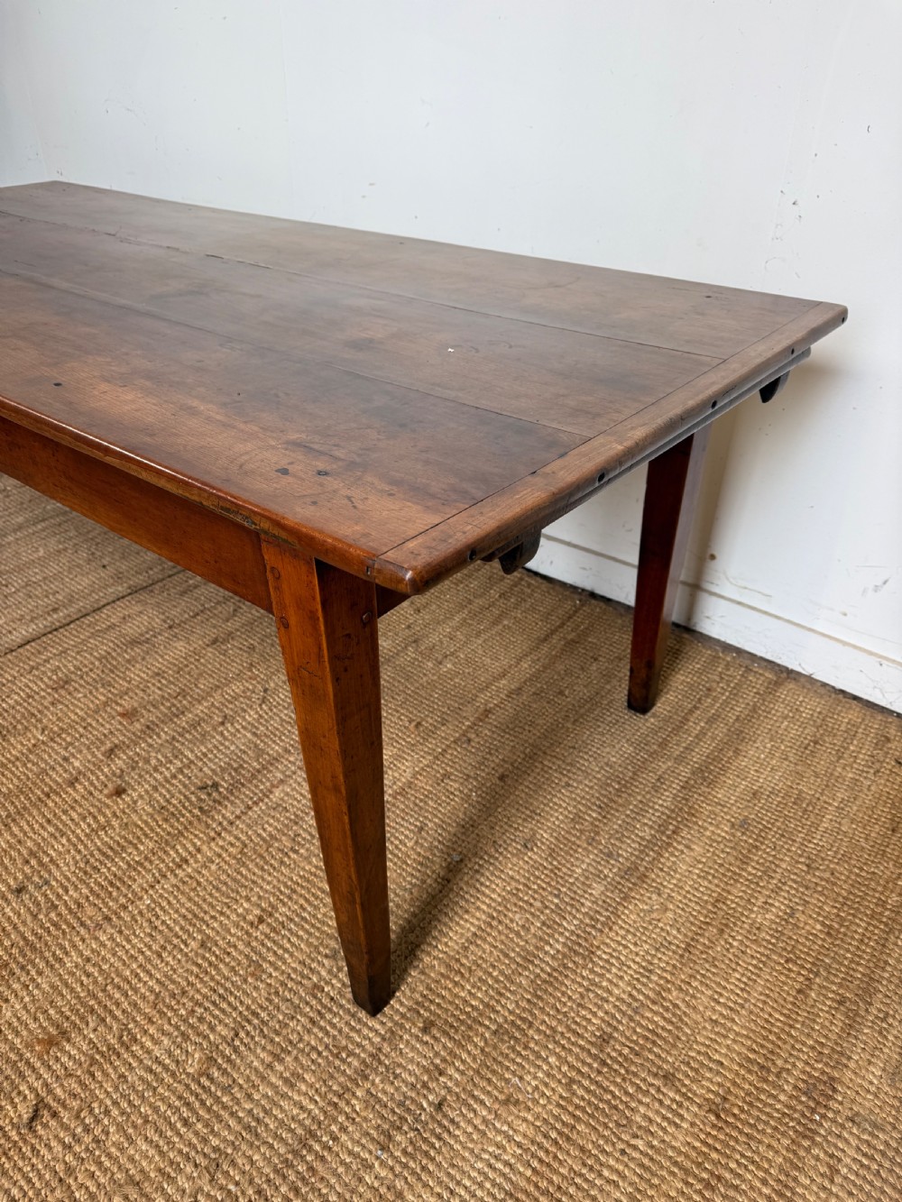 An antique French cherrywood farmhouse dining table featuring a plank top, single frieze drawer, and four square tapered legs. View V