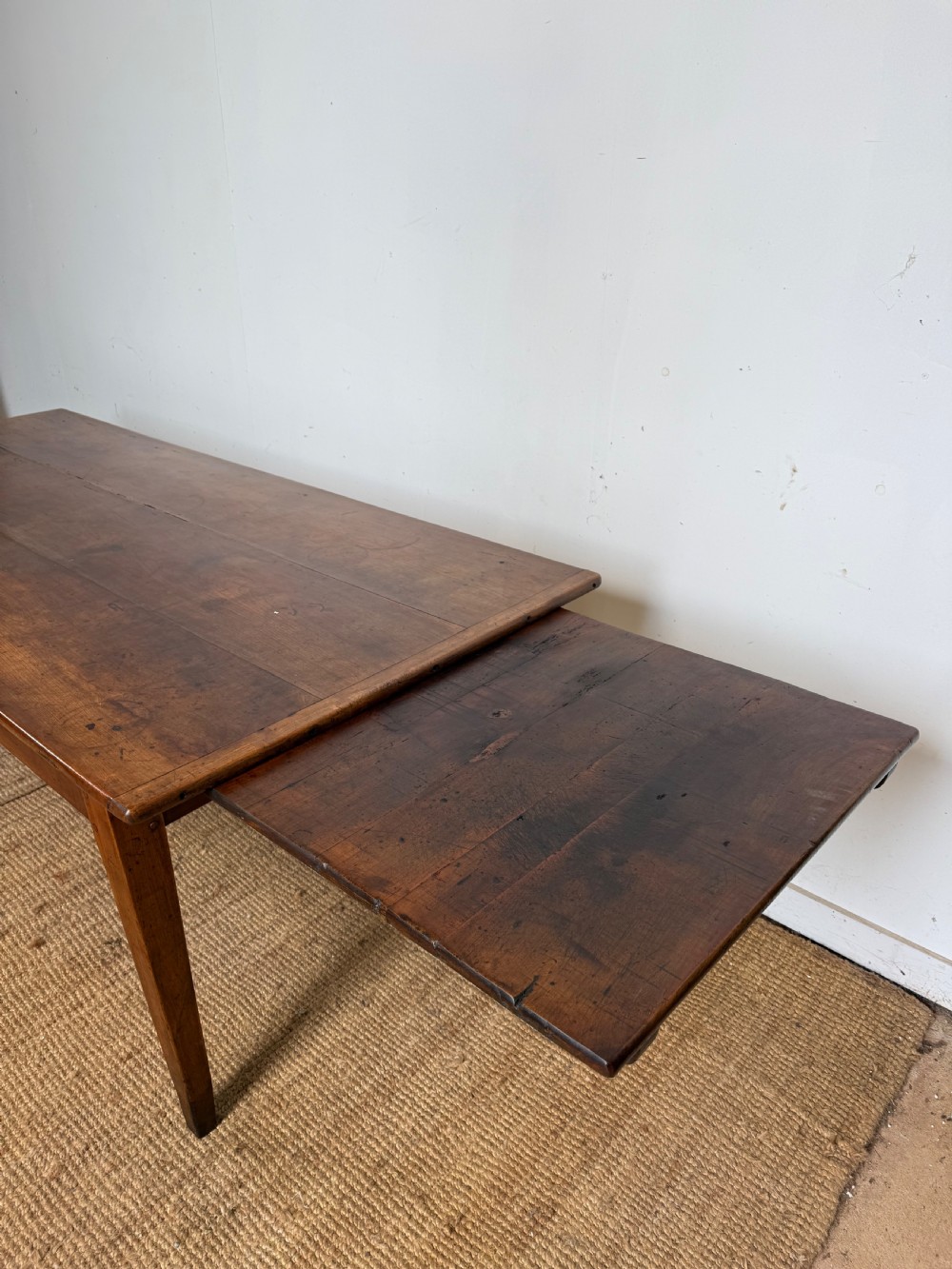 An antique French cherrywood farmhouse dining table featuring a plank top, single frieze drawer, and four square tapered legs. View VI