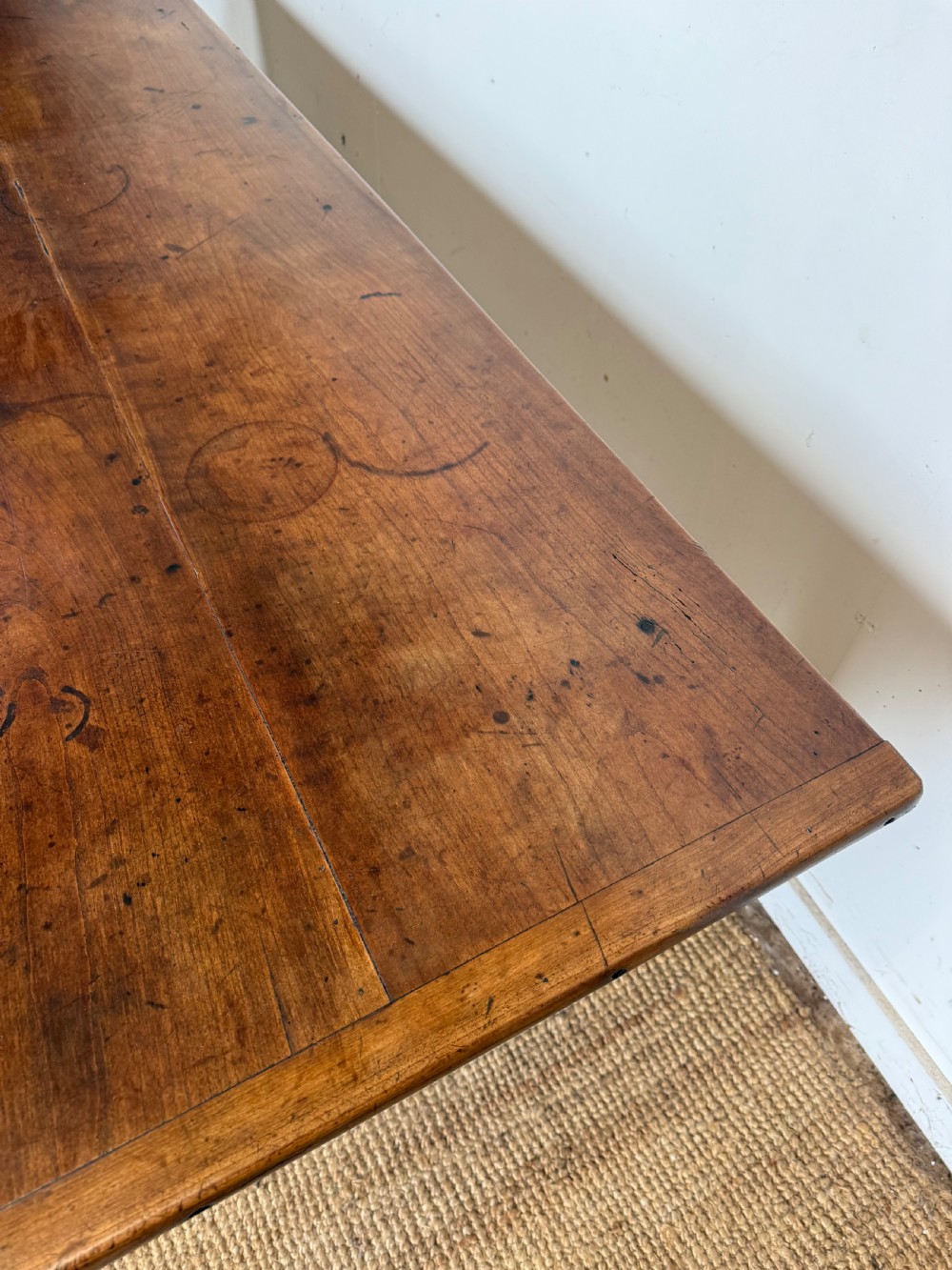 An antique French cherrywood farmhouse dining table featuring a plank top, single frieze drawer, and four square tapered legs. View X