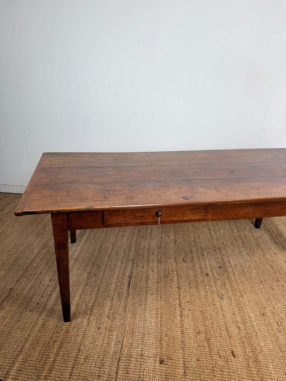 An antique French cherrywood farmhouse dining table featuring a plank top, single frieze drawer, and four square tapered legs. View XV