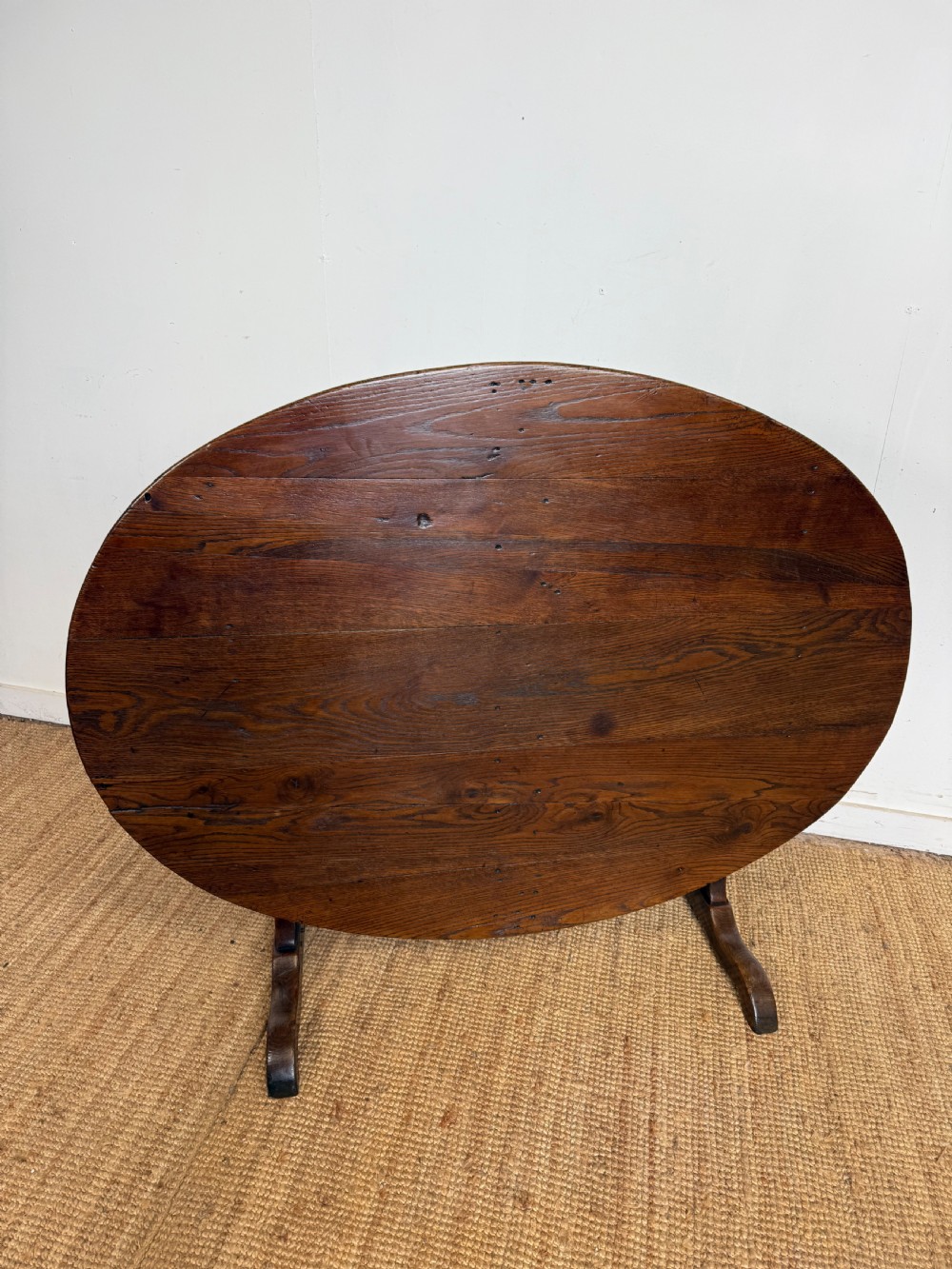 A 19th-century French dark oak Vendange table featuring a large oval tilting top set on a trestle base.
