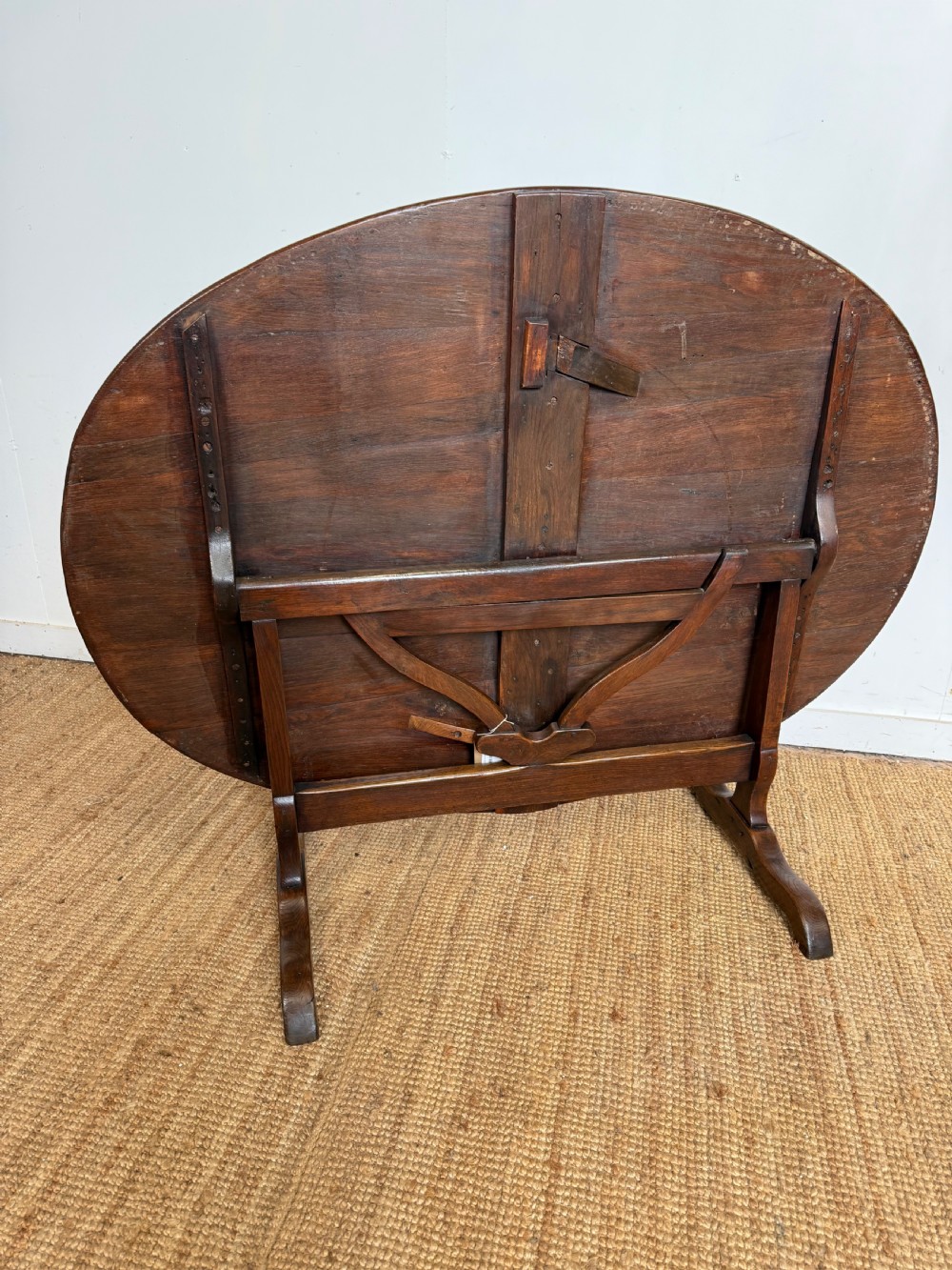 A 19th-century French dark oak Vendange table featuring a large oval tilting top set on a trestle base. View V