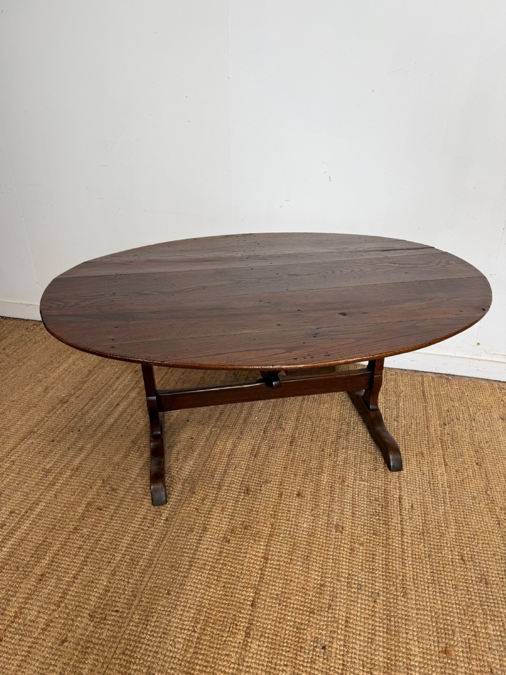 A 19th-century French dark oak Vendange table featuring a large oval tilting top set on a trestle base. View VI