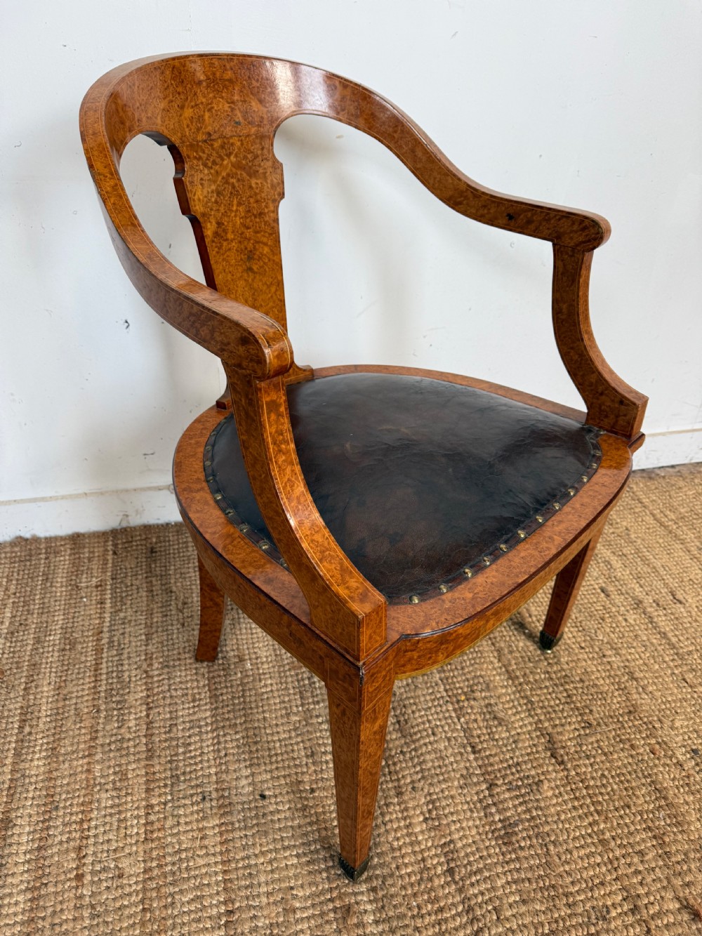 Late 19th-century burr elm desk chair featuring a curved backrest, central splat, dark leather studded upholstery, and tapered legs with brass feet. View II