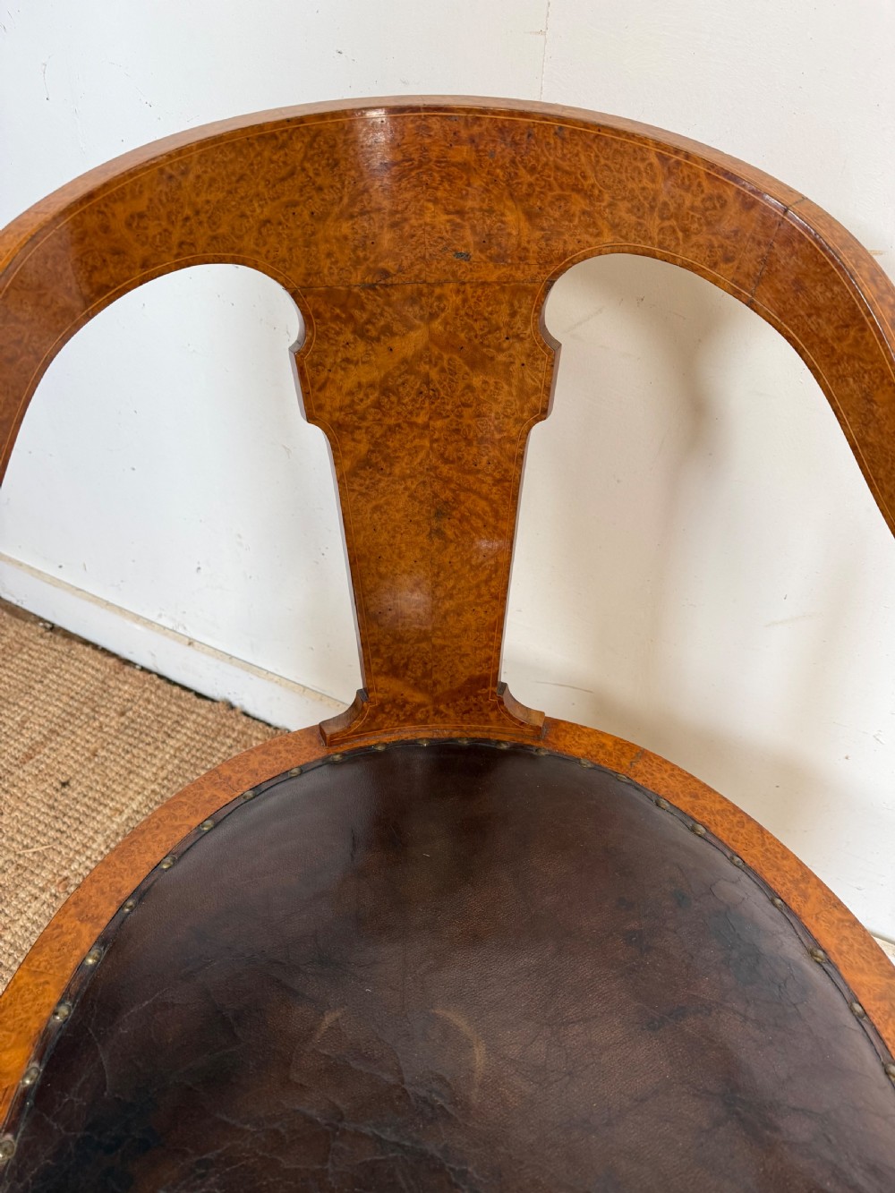 Late 19th-century burr elm desk chair featuring a curved backrest, central splat, dark leather studded upholstery, and tapered legs with brass feet. View III