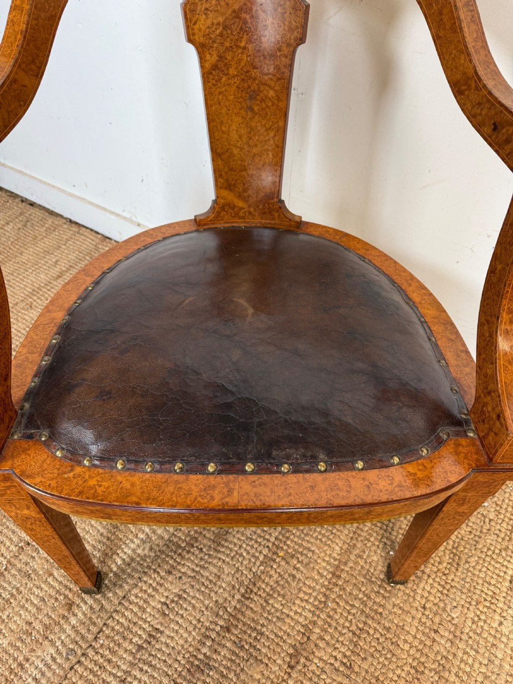 Late 19th-century burr elm desk chair featuring a curved backrest, central splat, dark leather studded upholstery, and tapered legs with brass feet. View IV