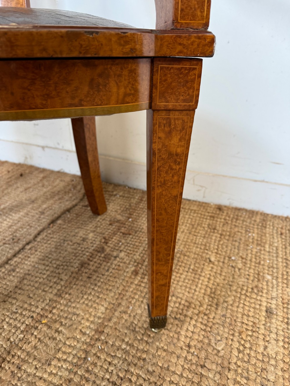 Late 19th-century burr elm desk chair featuring a curved backrest, central splat, dark leather studded upholstery, and tapered legs with brass feet. View V