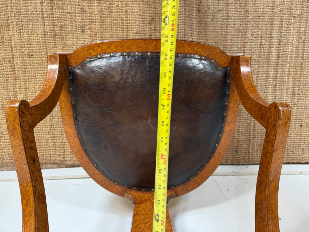 Late 19th-century burr elm desk chair featuring a curved backrest, central splat, dark leather studded upholstery, and tapered legs with brass feet. View XI
