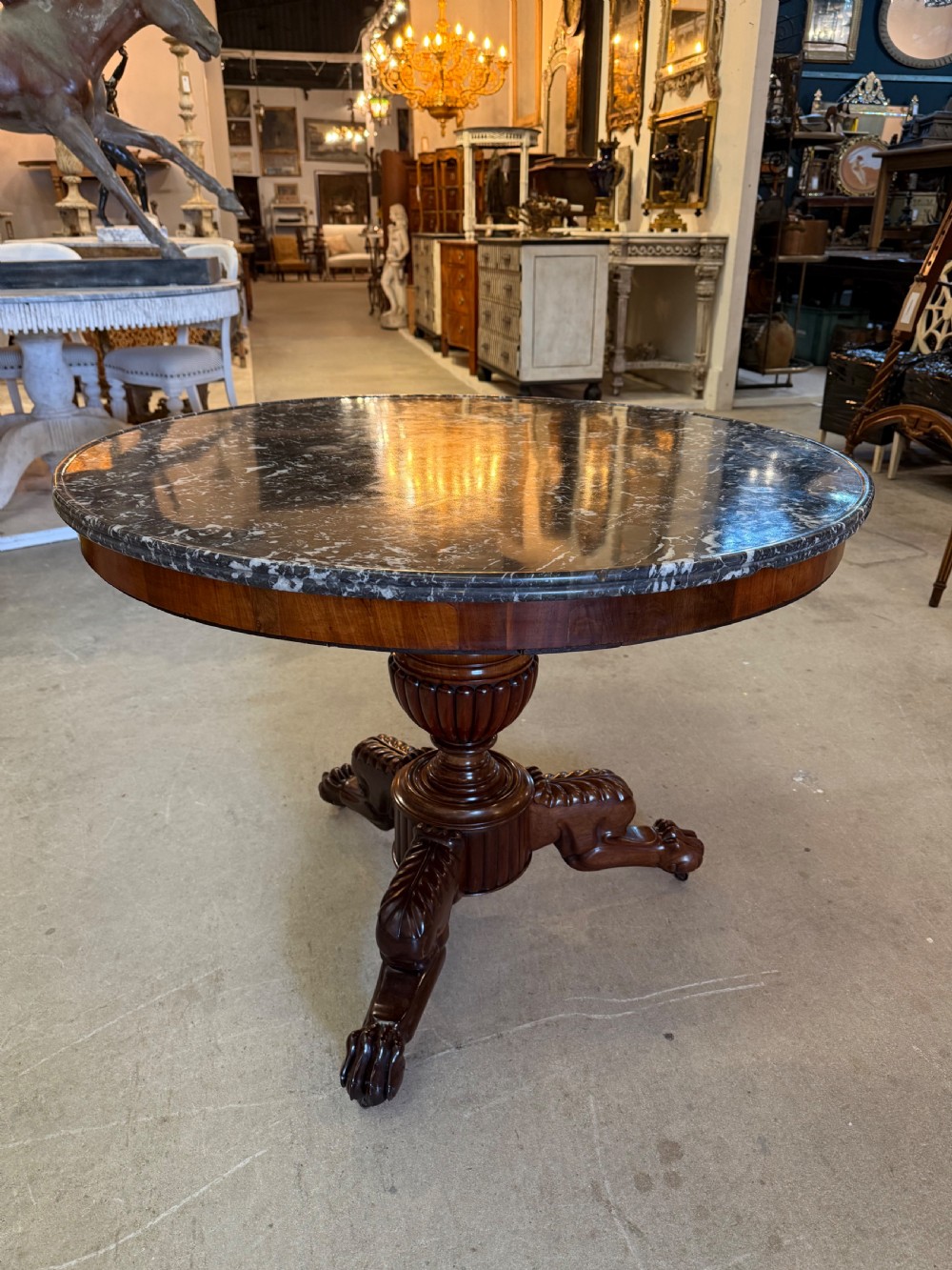 A 19th-century circular centre table featuring a dark veined marble top supported by a carved mahogany pedestal stem and a tripartite claw-foot base. View II