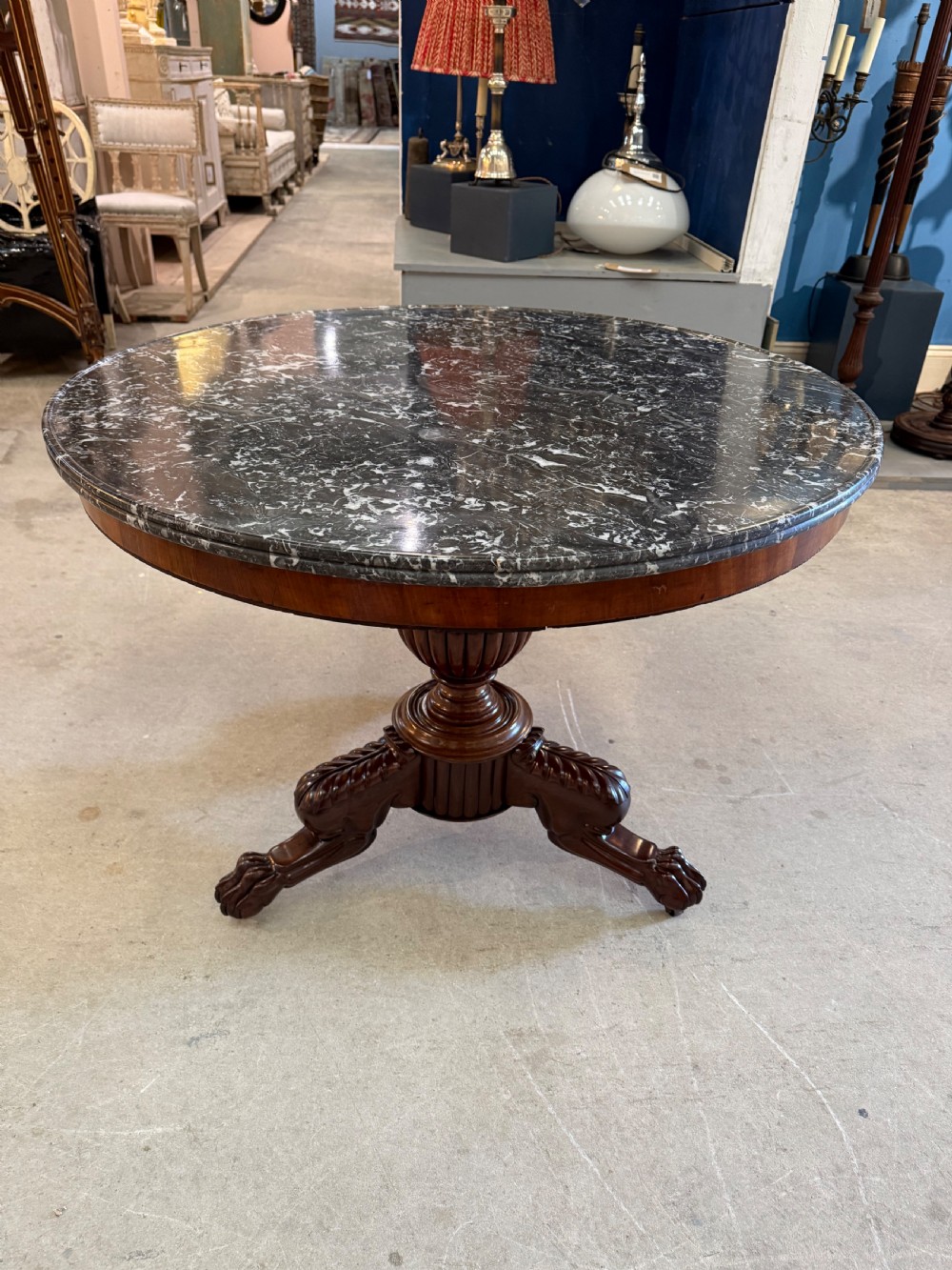 A 19th-century circular centre table featuring a dark veined marble top supported by a carved mahogany pedestal stem and a tripartite claw-foot base. View V