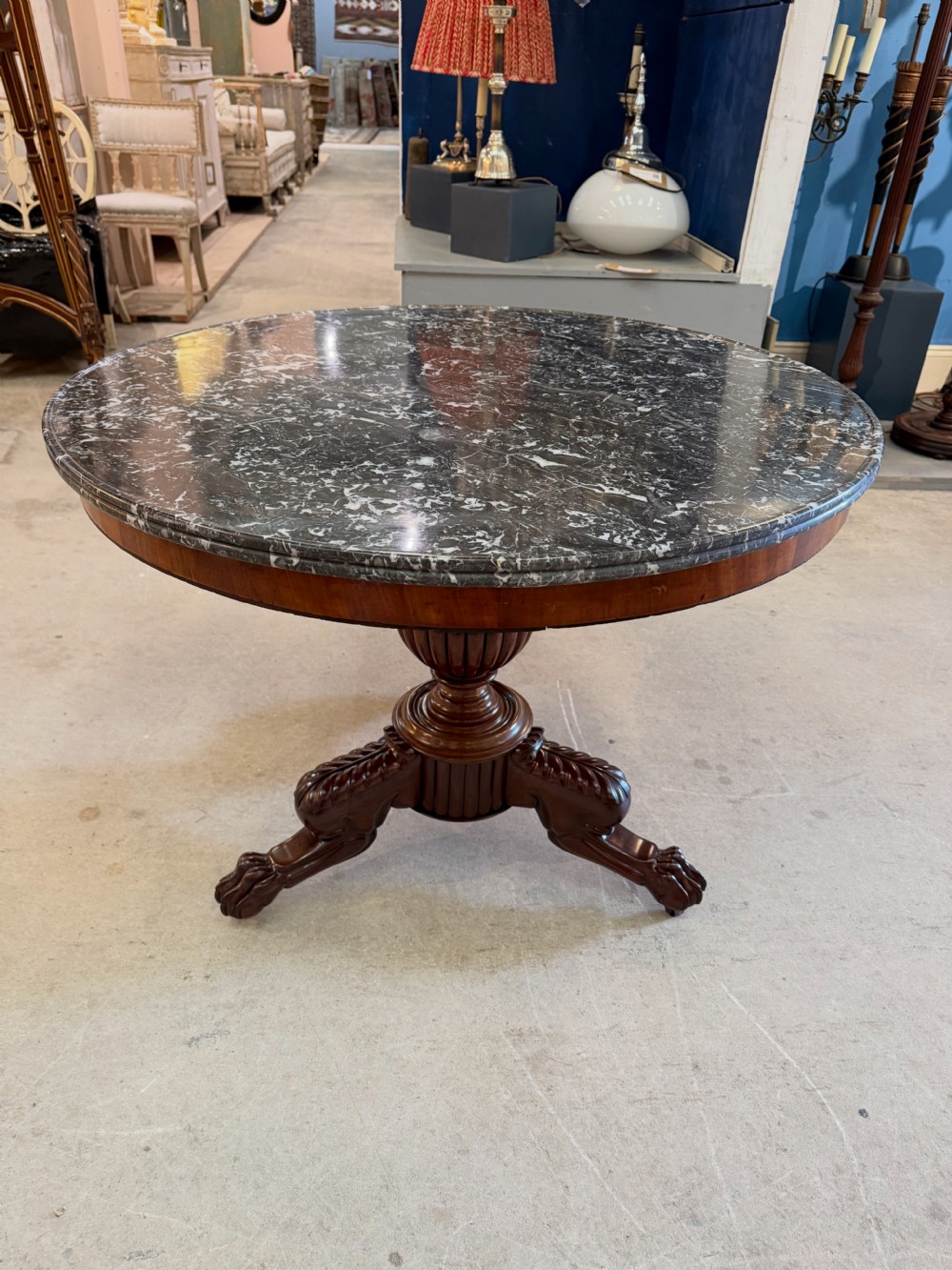 A 19th-century circular centre table featuring a dark veined marble top supported by a carved mahogany pedestal stem and a tripartite claw-foot base. View X