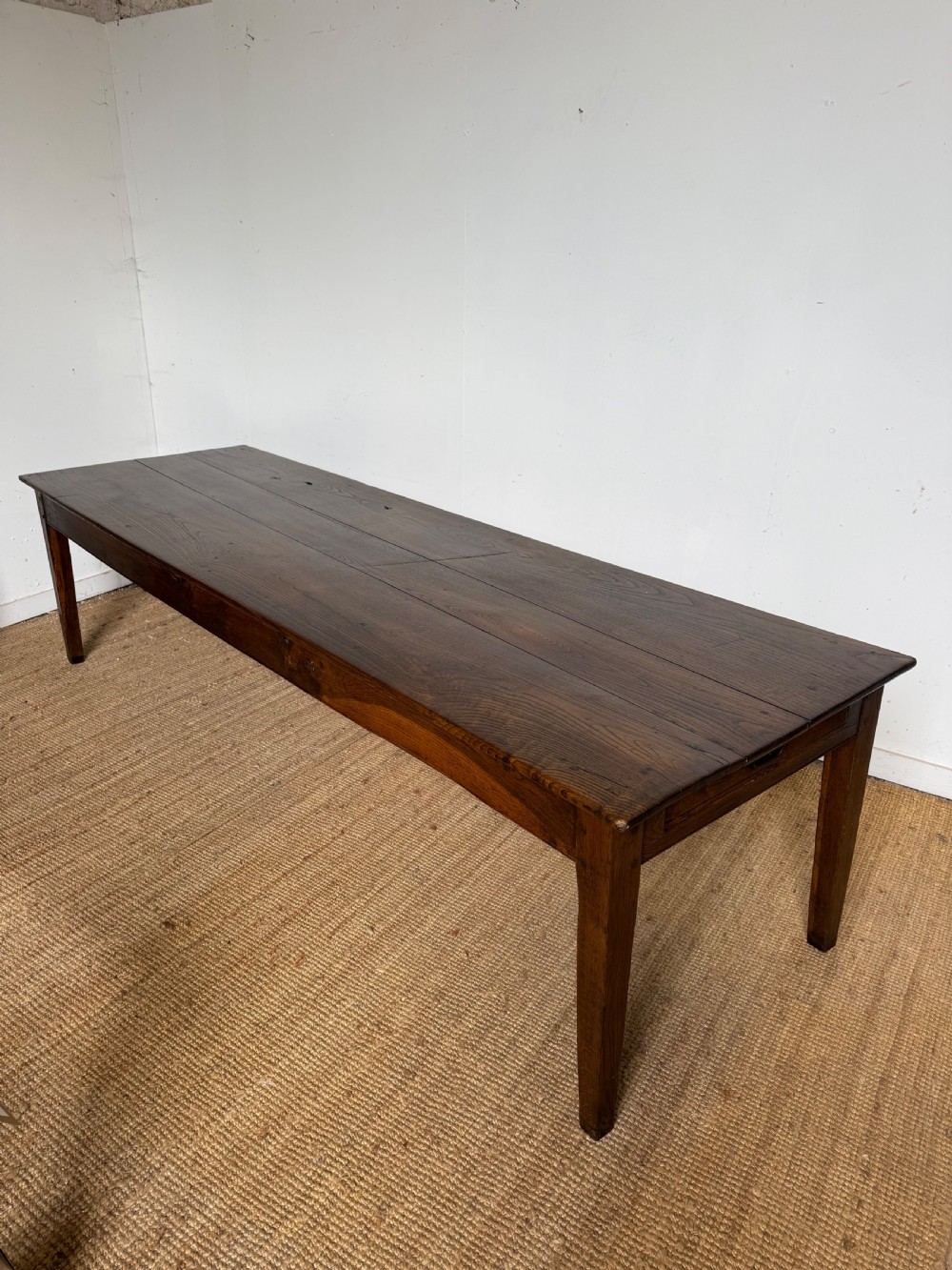 A three metre long antique oak farmhouse table featuring a three-plank top and straight tapered square legs.