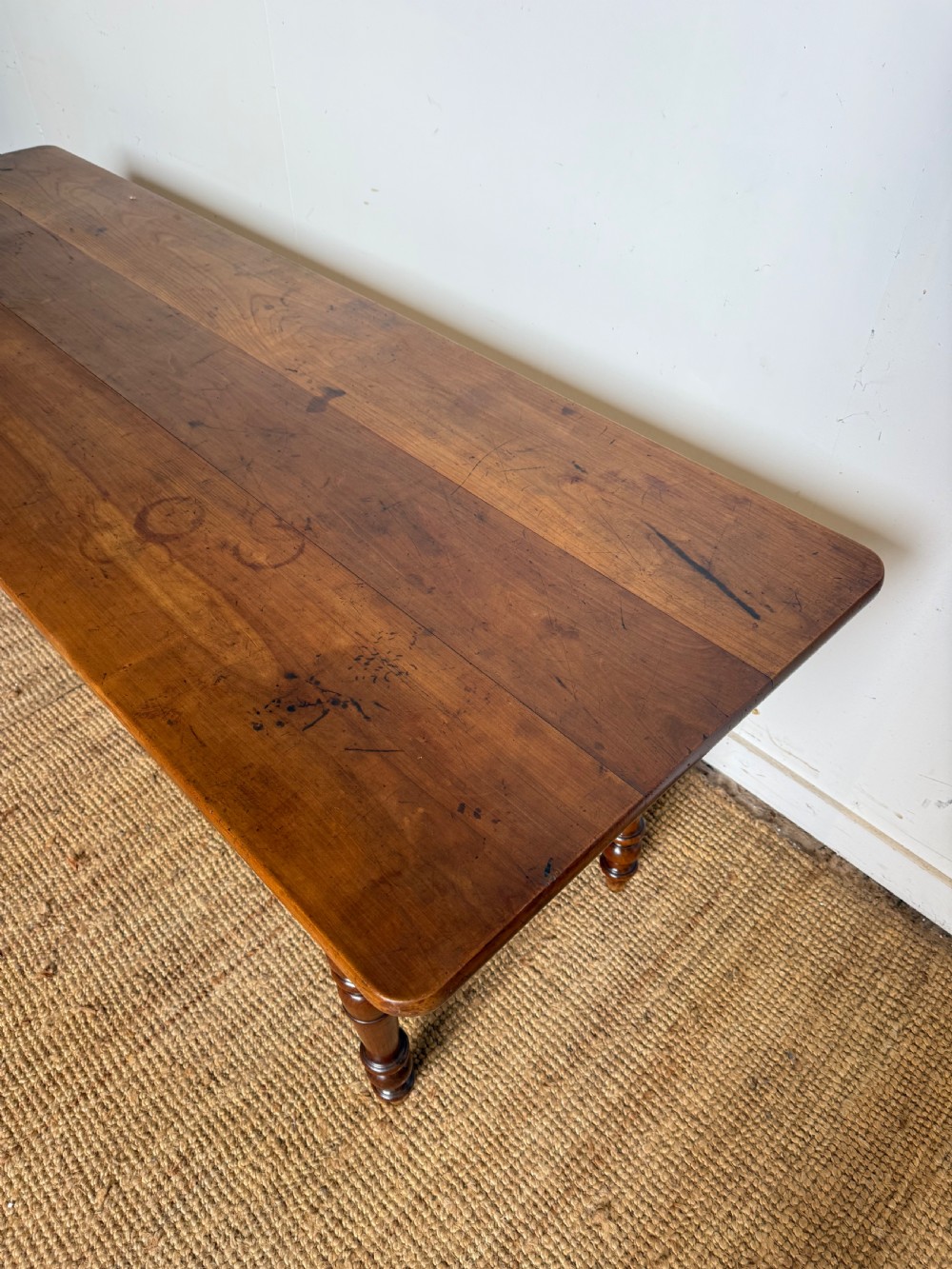 An antique rectangular cherrywood console table with a plank top, single central drawer with a turned knob, and four baluster turned legs. View II