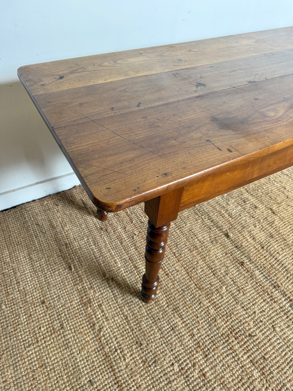 An antique rectangular cherrywood console table with a plank top, single central drawer with a turned knob, and four baluster turned legs. View VI